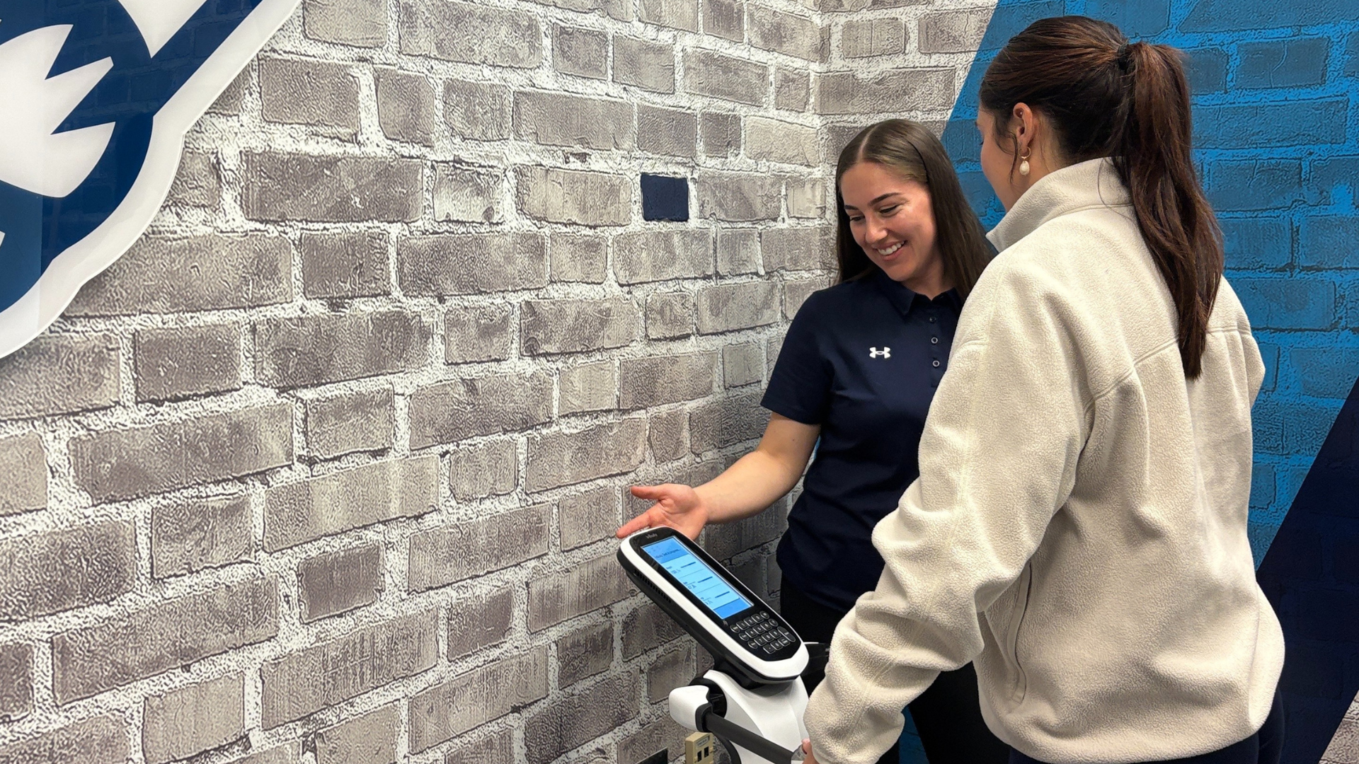 Two women are using an InBody scan machine, with one explaining the results displayed on the screen to the woman receiving the test.