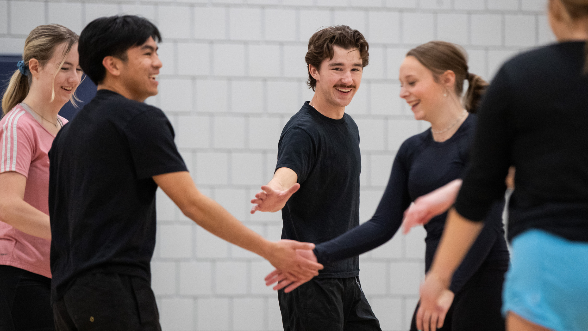 Intramural participants - two boys and two girls - smiling and high fiving during their volleyball game.