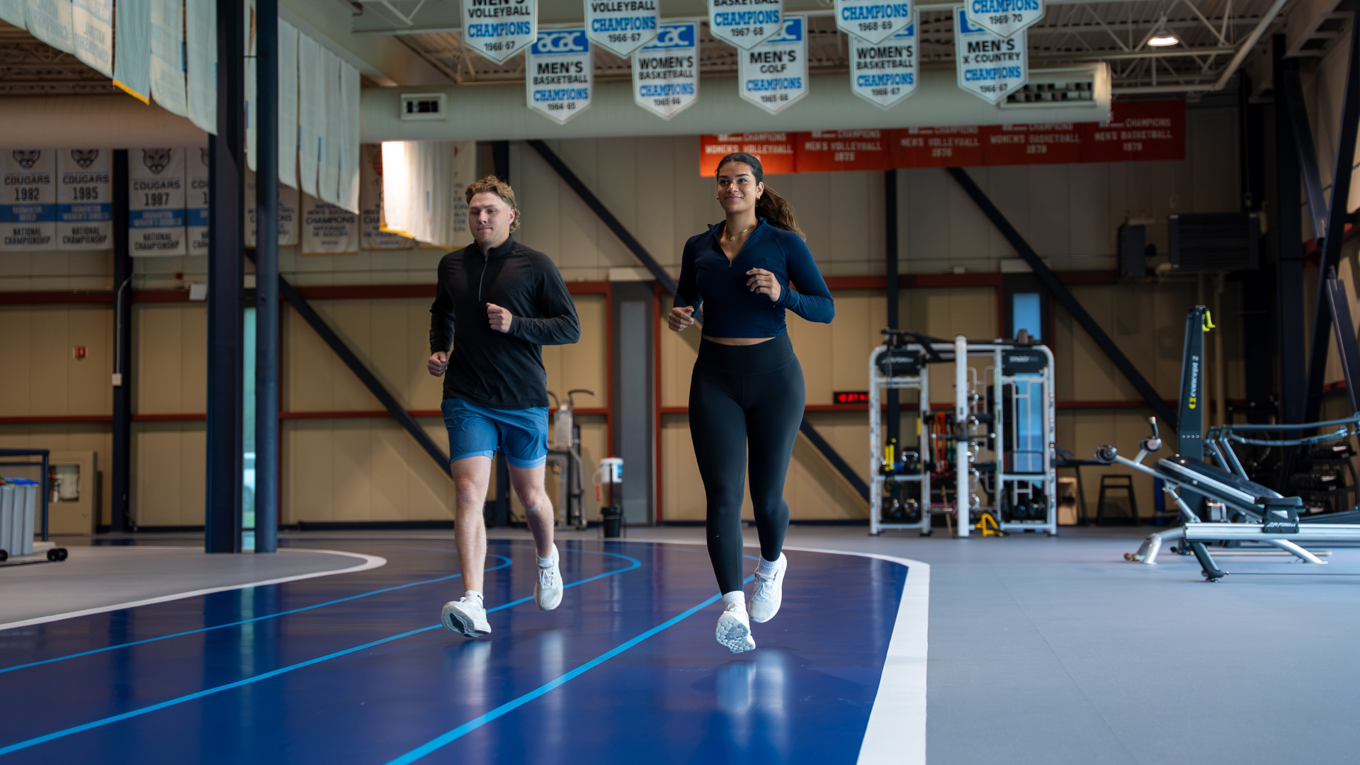 Two students, a male and female, running on MRU running track