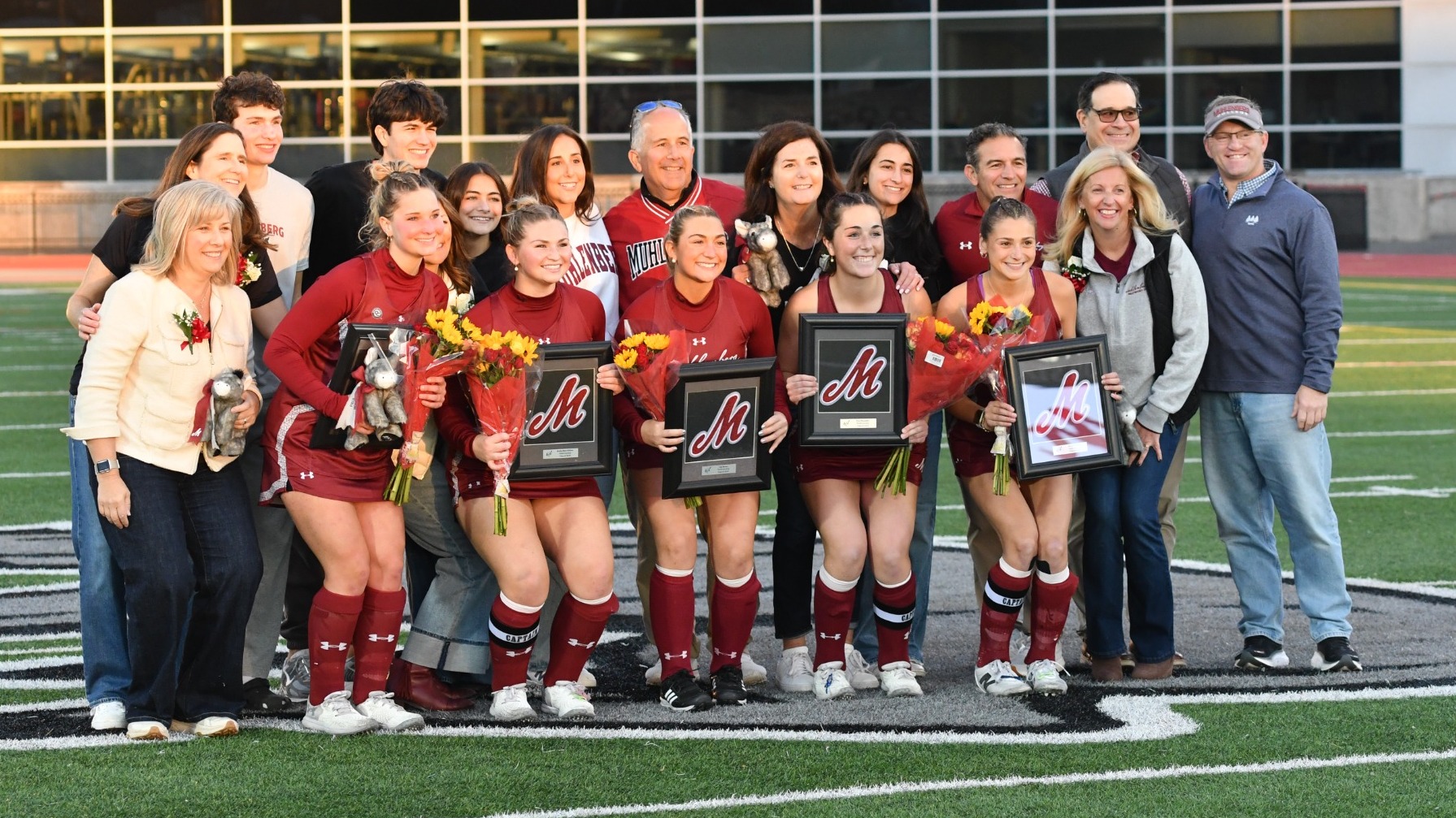 Muhlenberg field hockey's five seniors and their relatives huddle for a photo