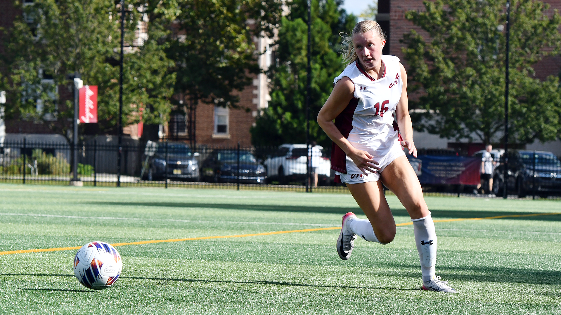 A soccer player in a white uniform looks up the field
