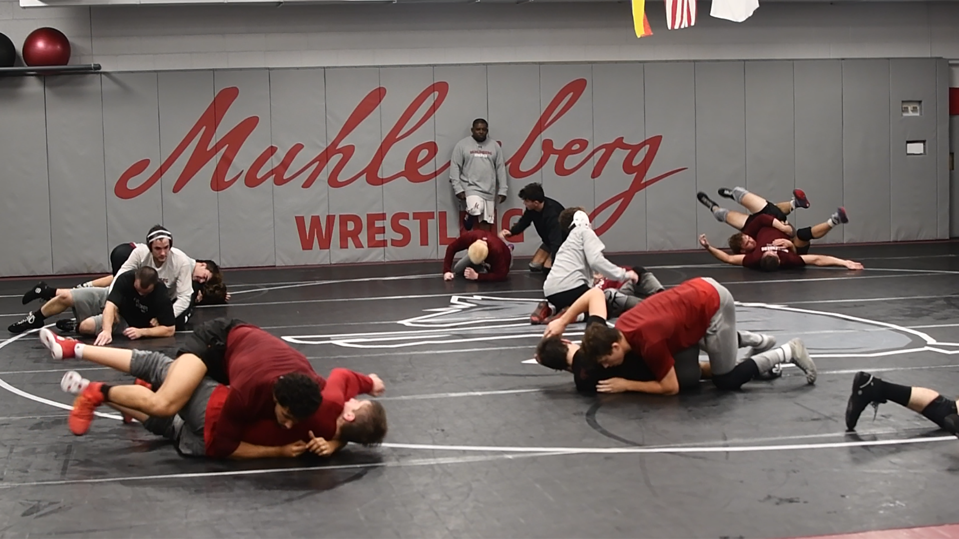 wrestlers practice in a room with Muhlenberg wrestling on the back wall