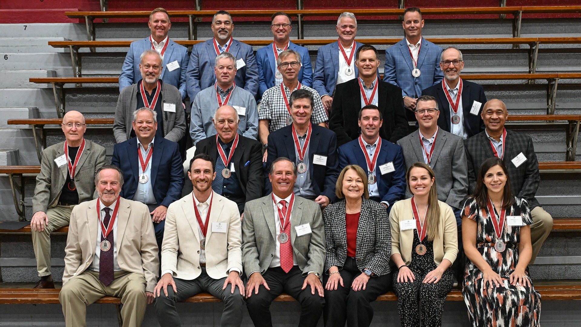 four rows of Hall of Fame inductees with medallions around their necks pose for a group picture