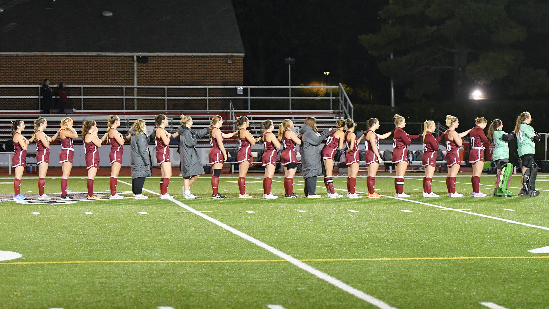 field hockey players in red uniforms stand in a line