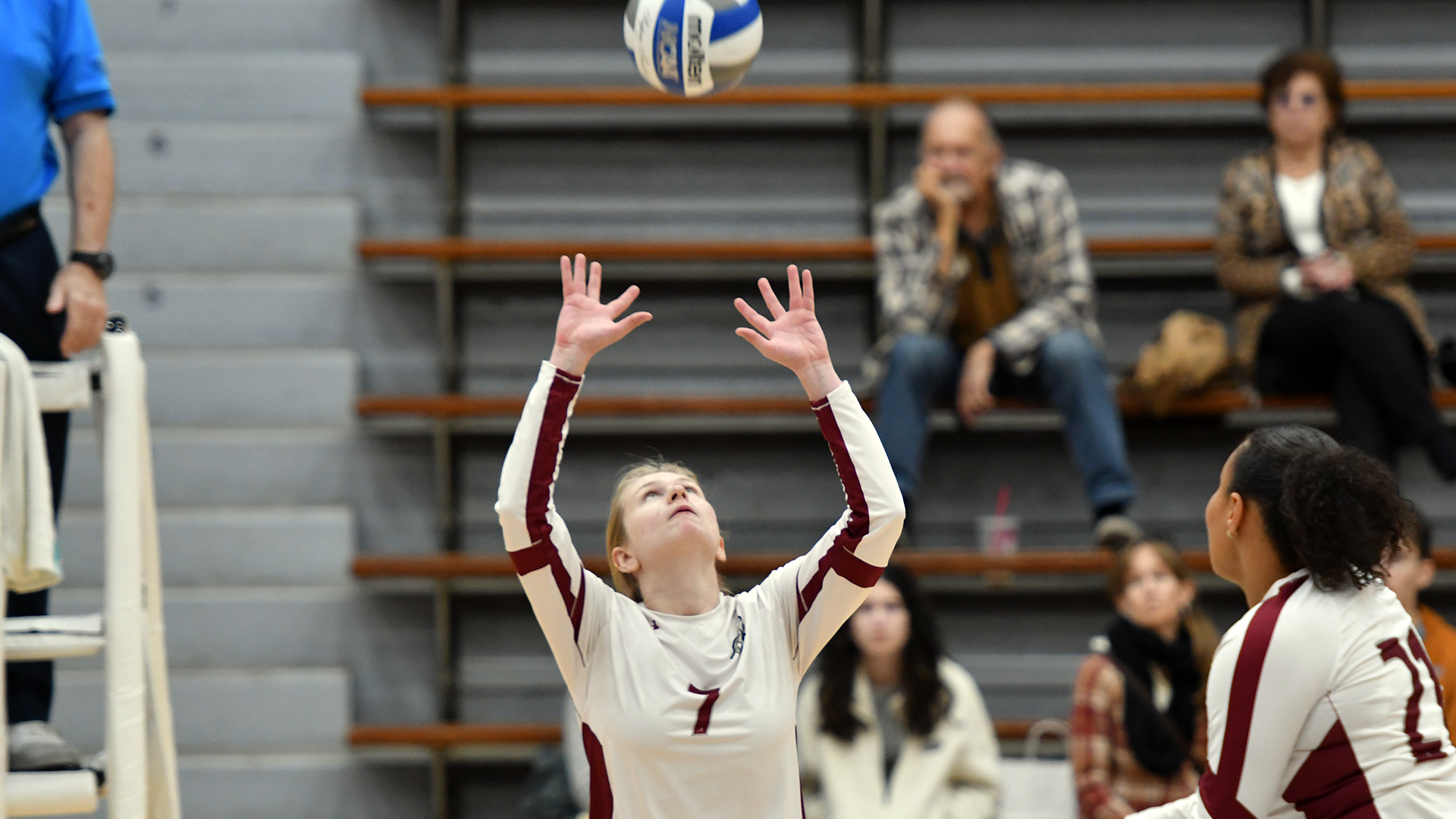a volleyball player in a white uniform prepares to set the ball
