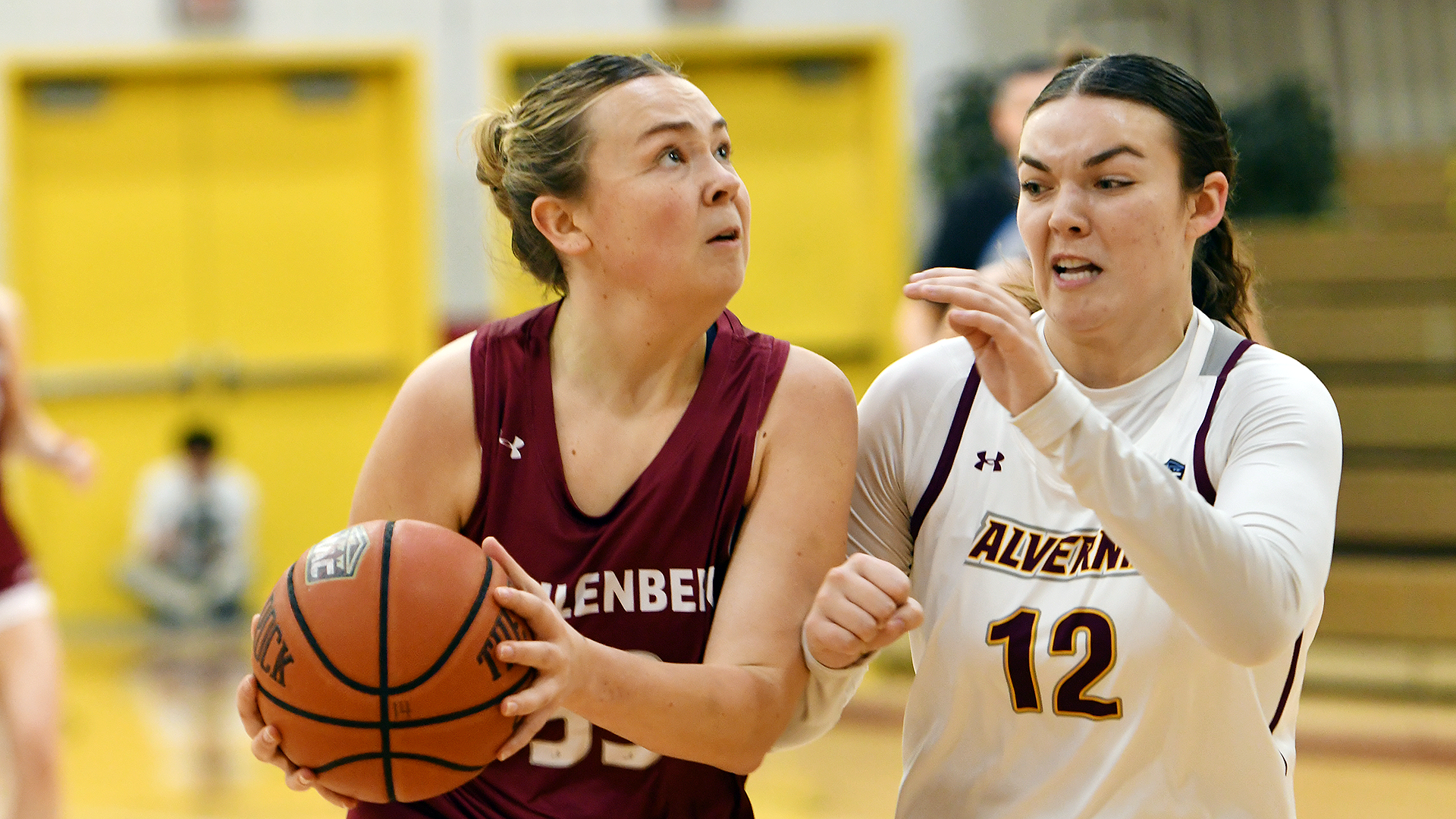 a basketball player in a red uniform drives while being guard by a player in a white uniform on her left