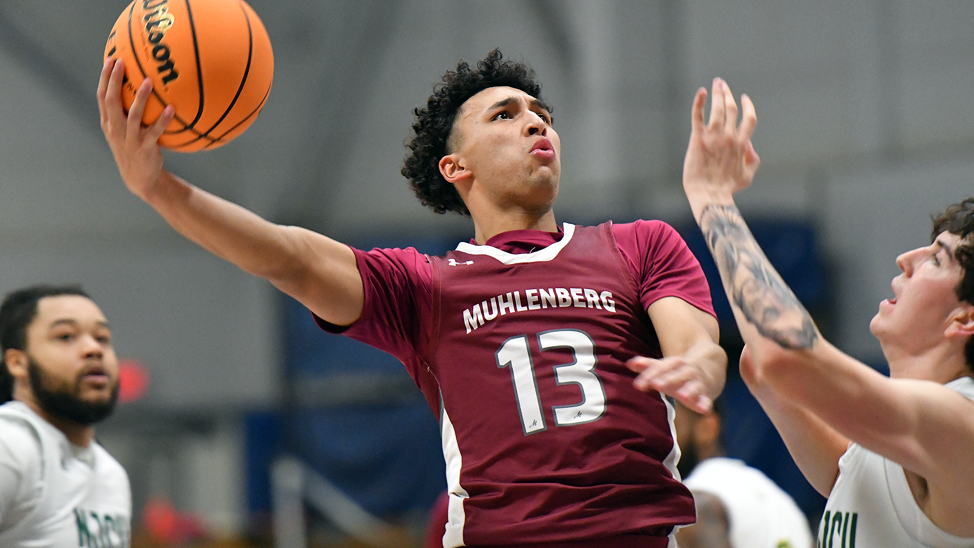 a basketball player in a red uniform takes a hook shot over a player in a white uniform