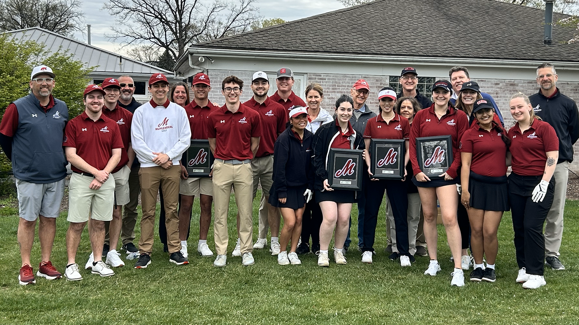 golfers in red polo shirts, four holding framed plaques, pose for a team picture