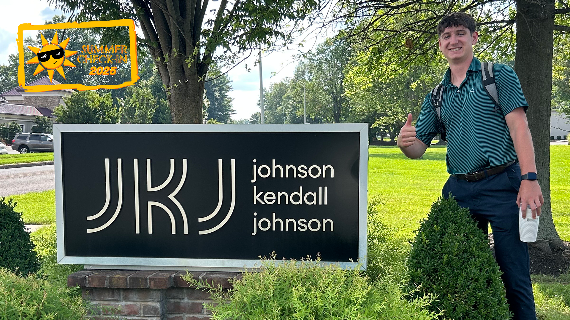 A young man in a teal polo shirt stands outdoors in front of a sign that reads JKJ johnson kendall johnson