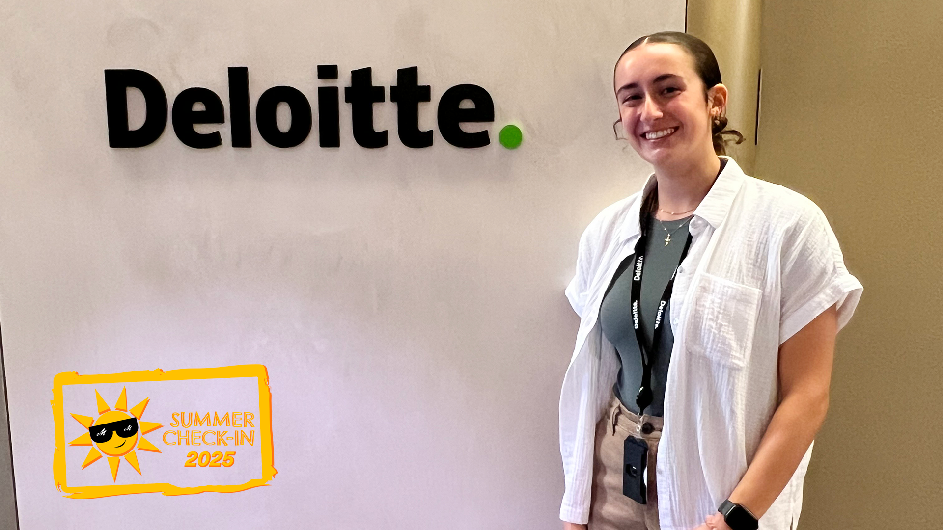A young woman in a white shirt stands in front of a white wall with the word Deloitte on it