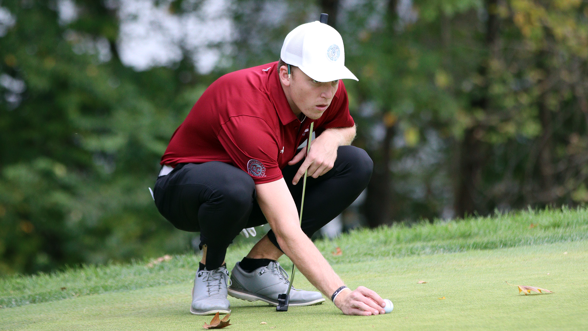A golfer in a red shirt lines up a putt