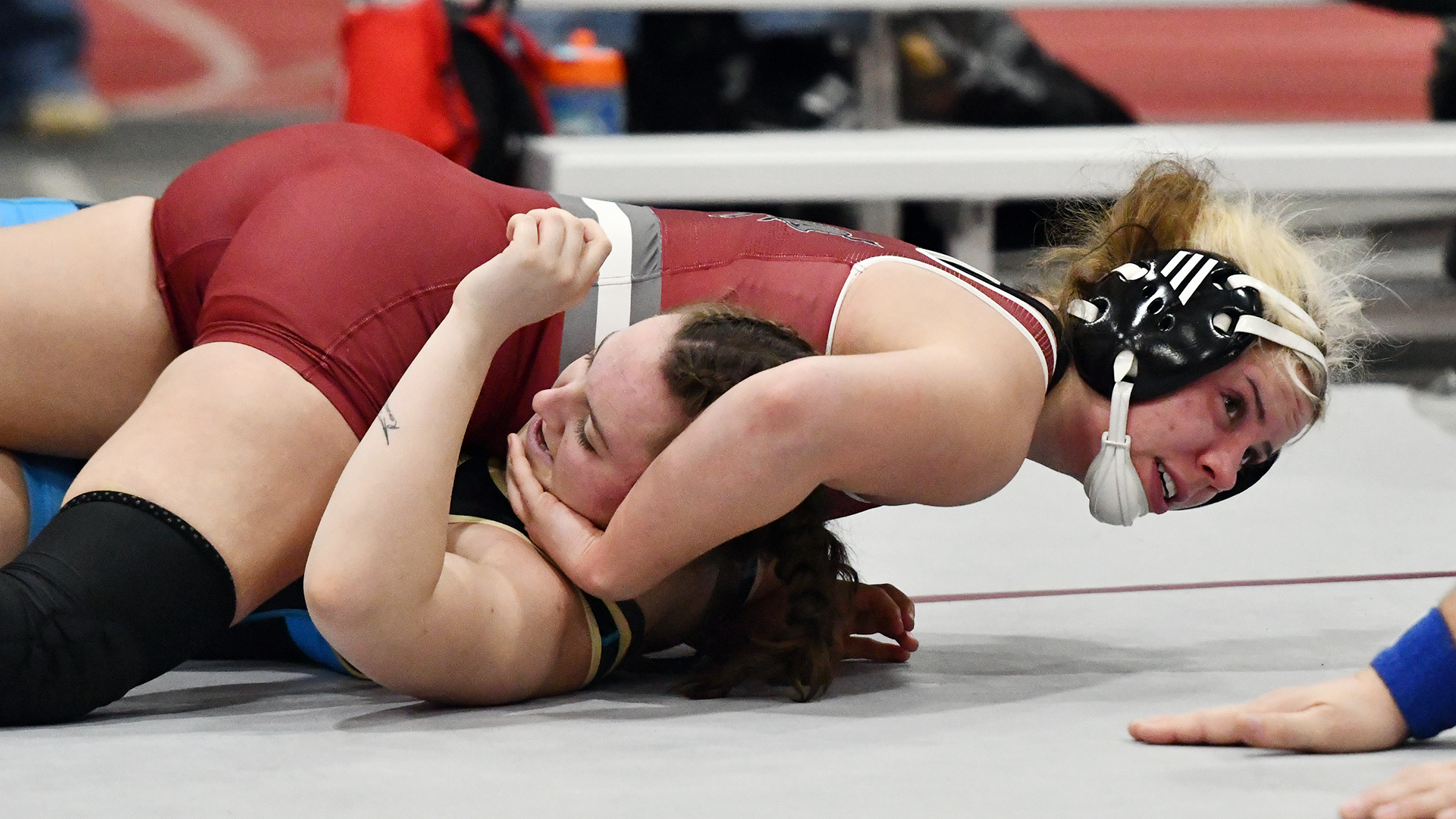 a wrestler in a red singlet pins her opponent