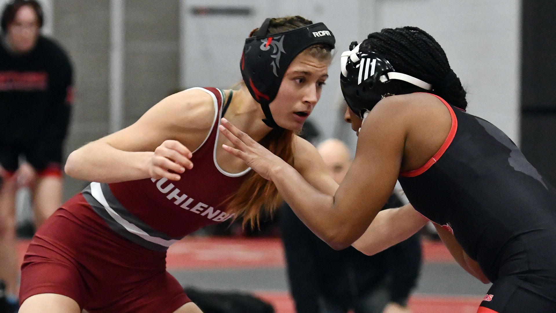 a wrestling in a red singlet in her stance against a wrestler in a black singlet
