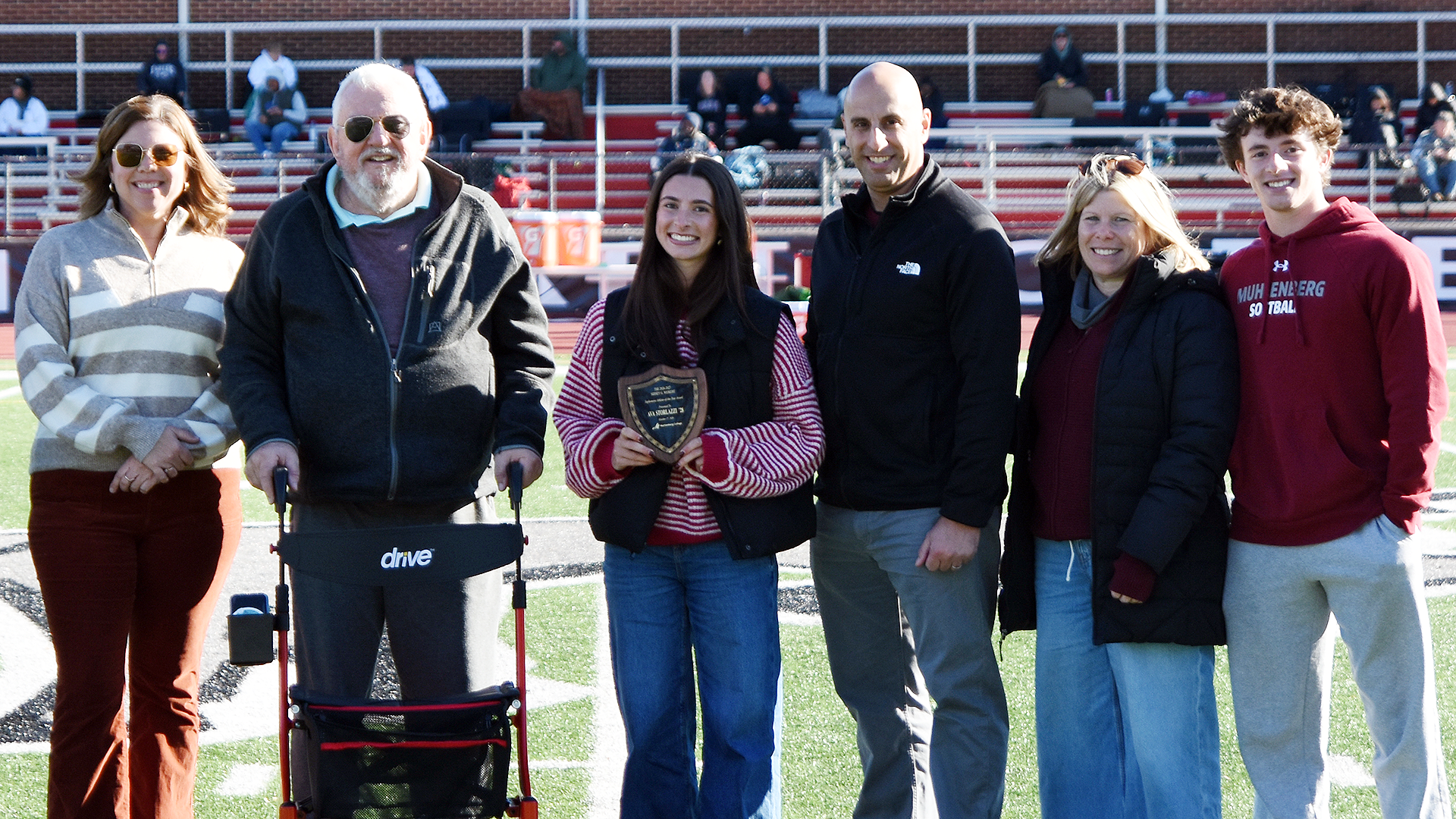 an awards presentation on a sunny day on a green field, with six people standing in a row