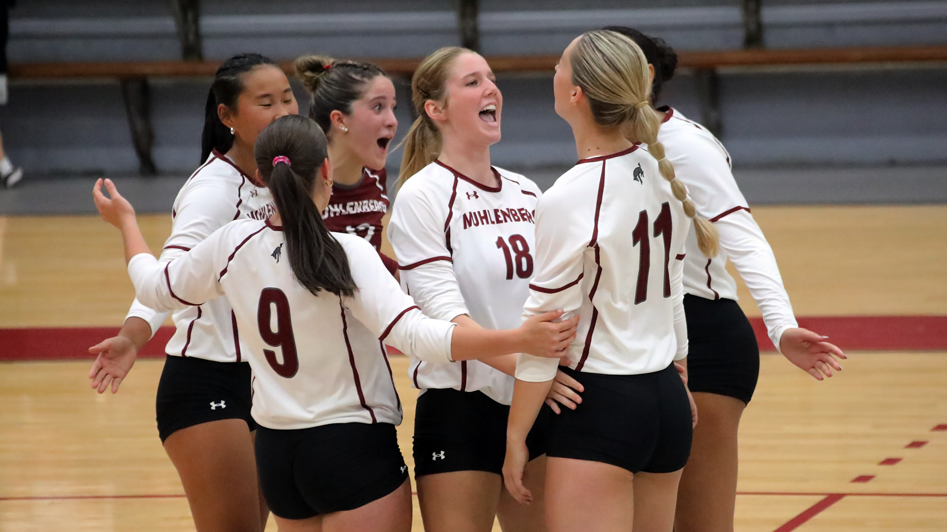 volleyball players in white uniforms celebrating a point