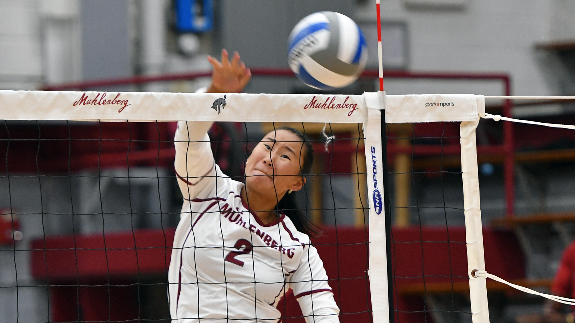 a volleyball player in a white uniform following through on a hit as the ball goes over the net