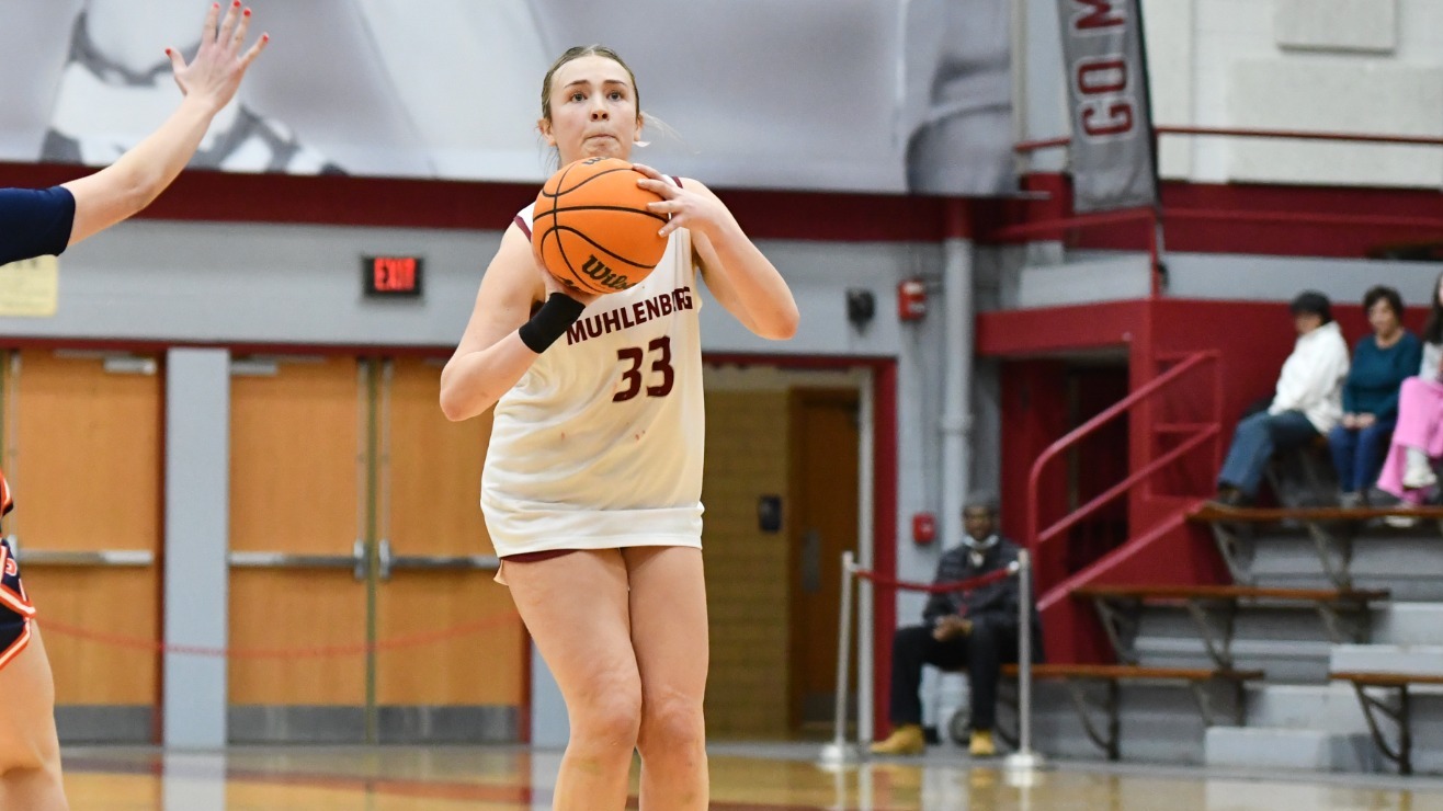 A player in a white jersey lines up to shoot the ball from three point territory