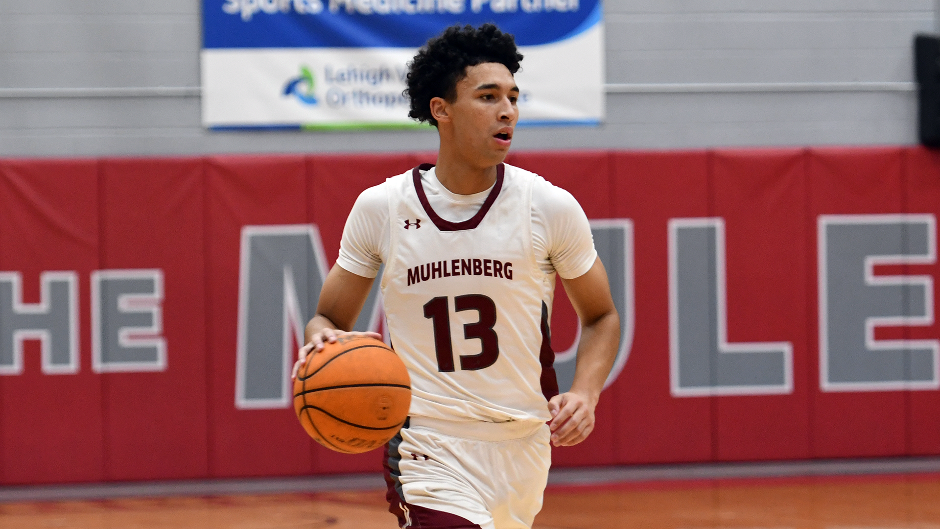 a men's basketball player in a white uniform wearing number 13 dribbling the ball