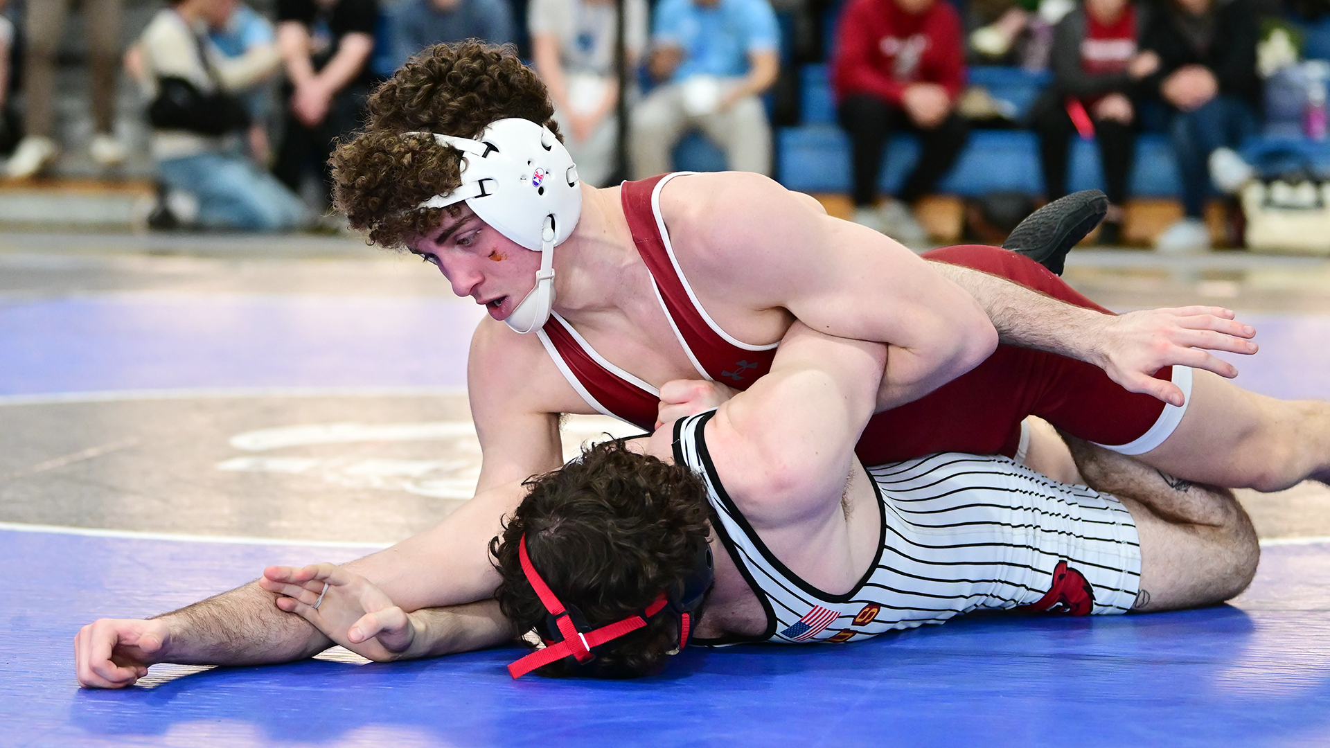a wrestler in a red singlet rides one in a white singlet with black pinstripes