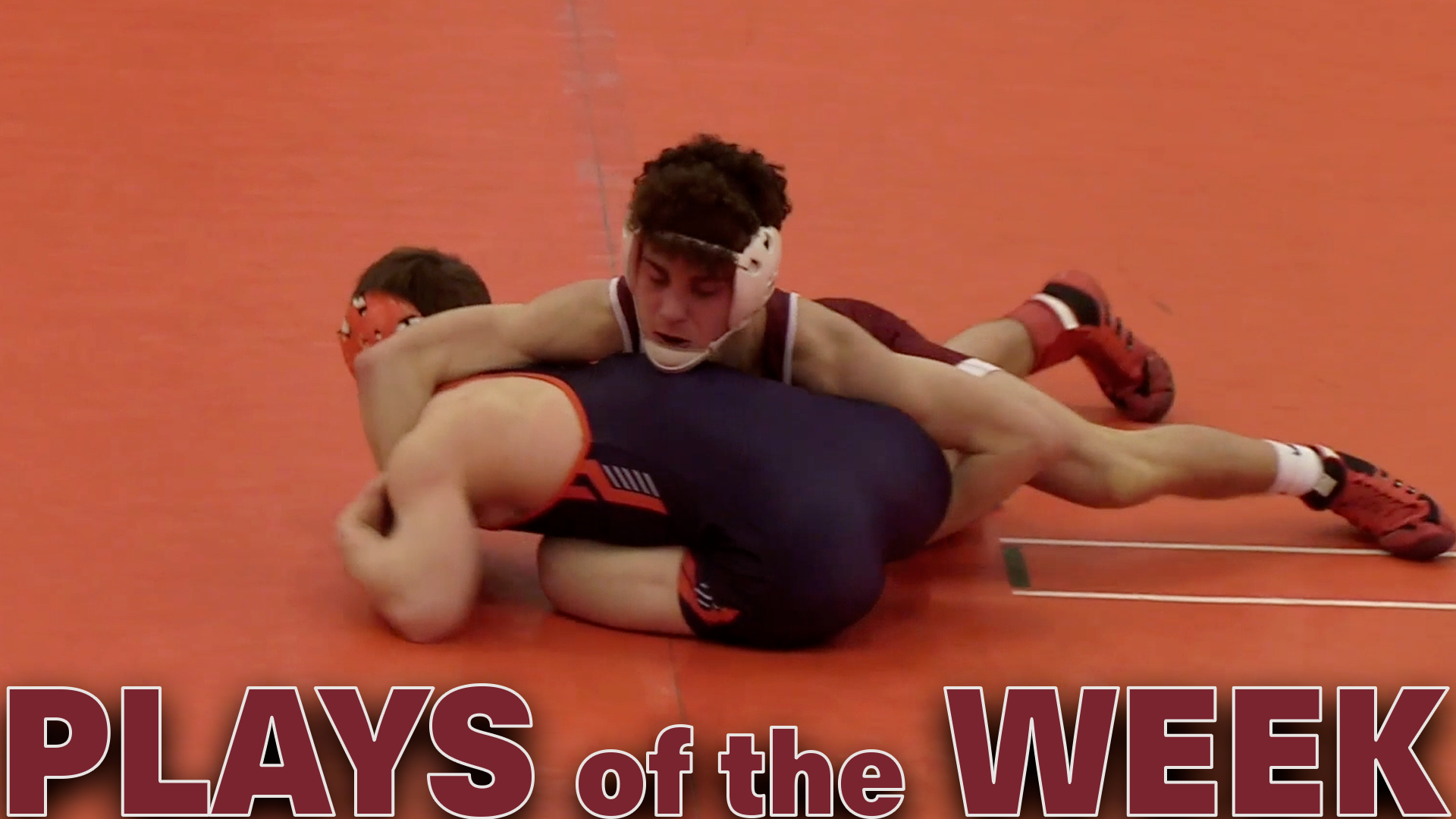 a male wrestler in a red singlet rides one in a blue singlet on an orange mat, with the text Plays of the Week in red at the bottom