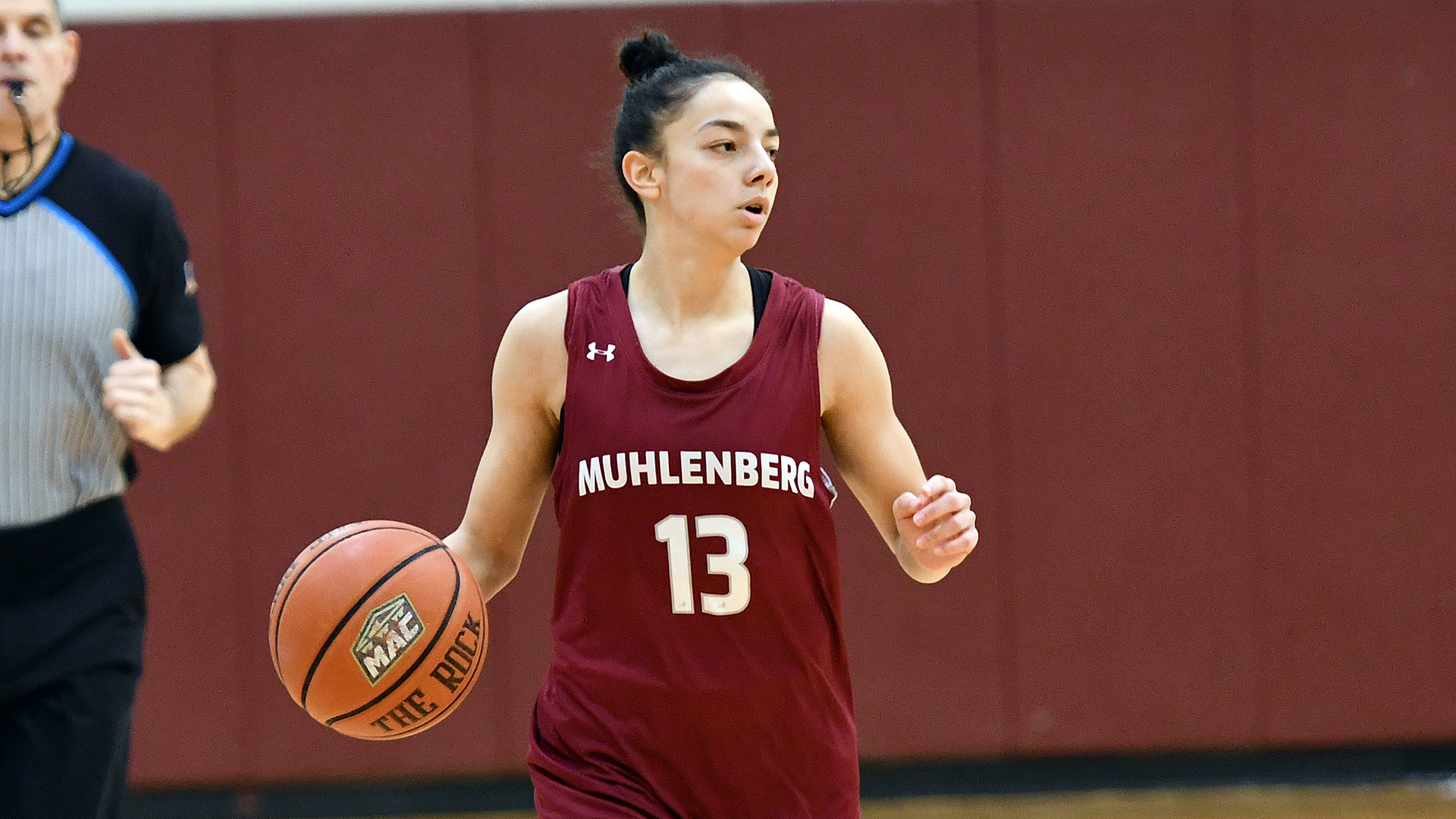 a basketball player in a red jersey dribbling up the court