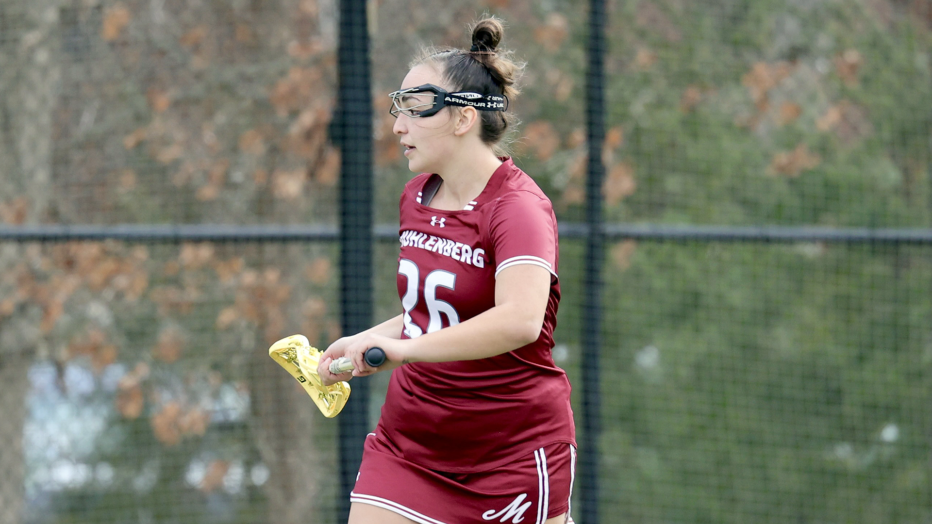 a women's lacrosse player in a red uniform facing left 