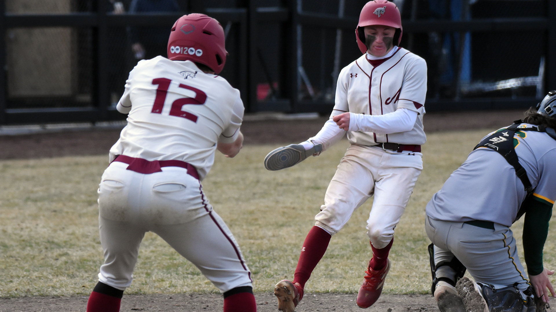 a baseball player in a white uniform runs around the catcher to score a run