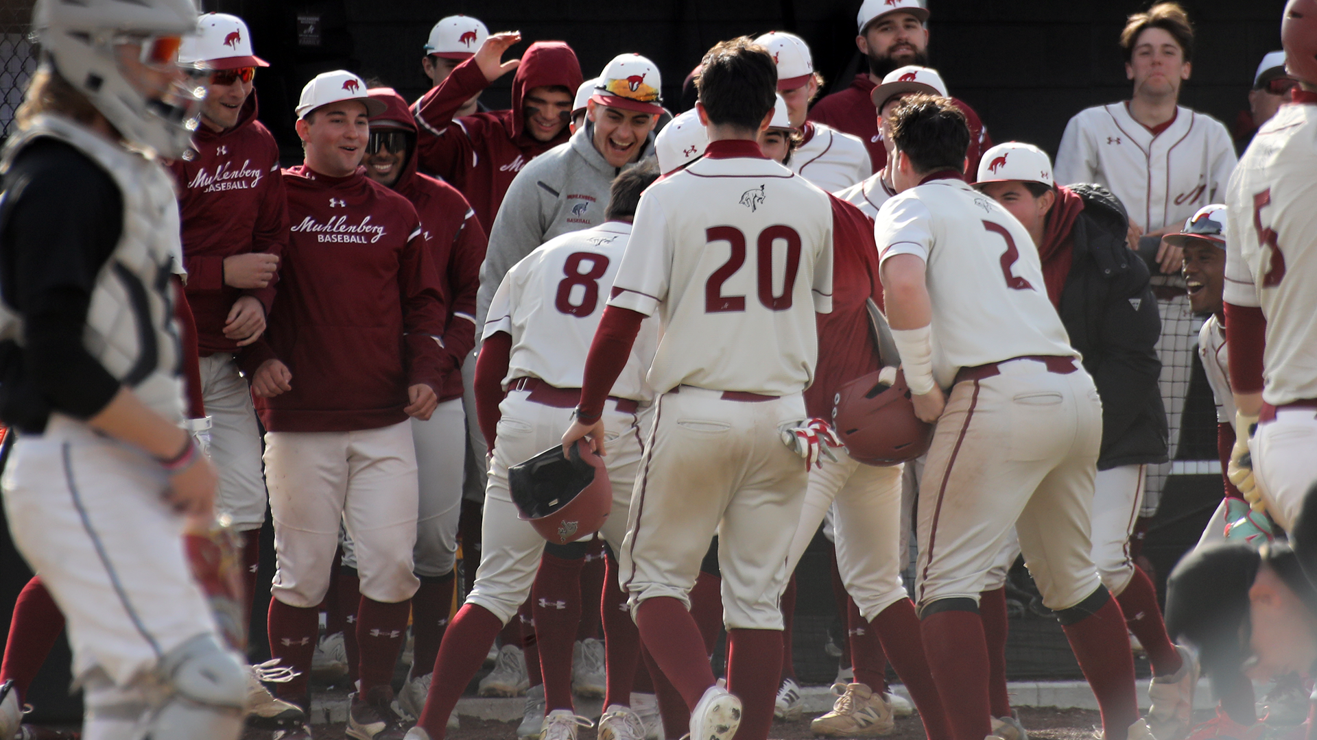baseball players in white jerseys celebrate in the dugout