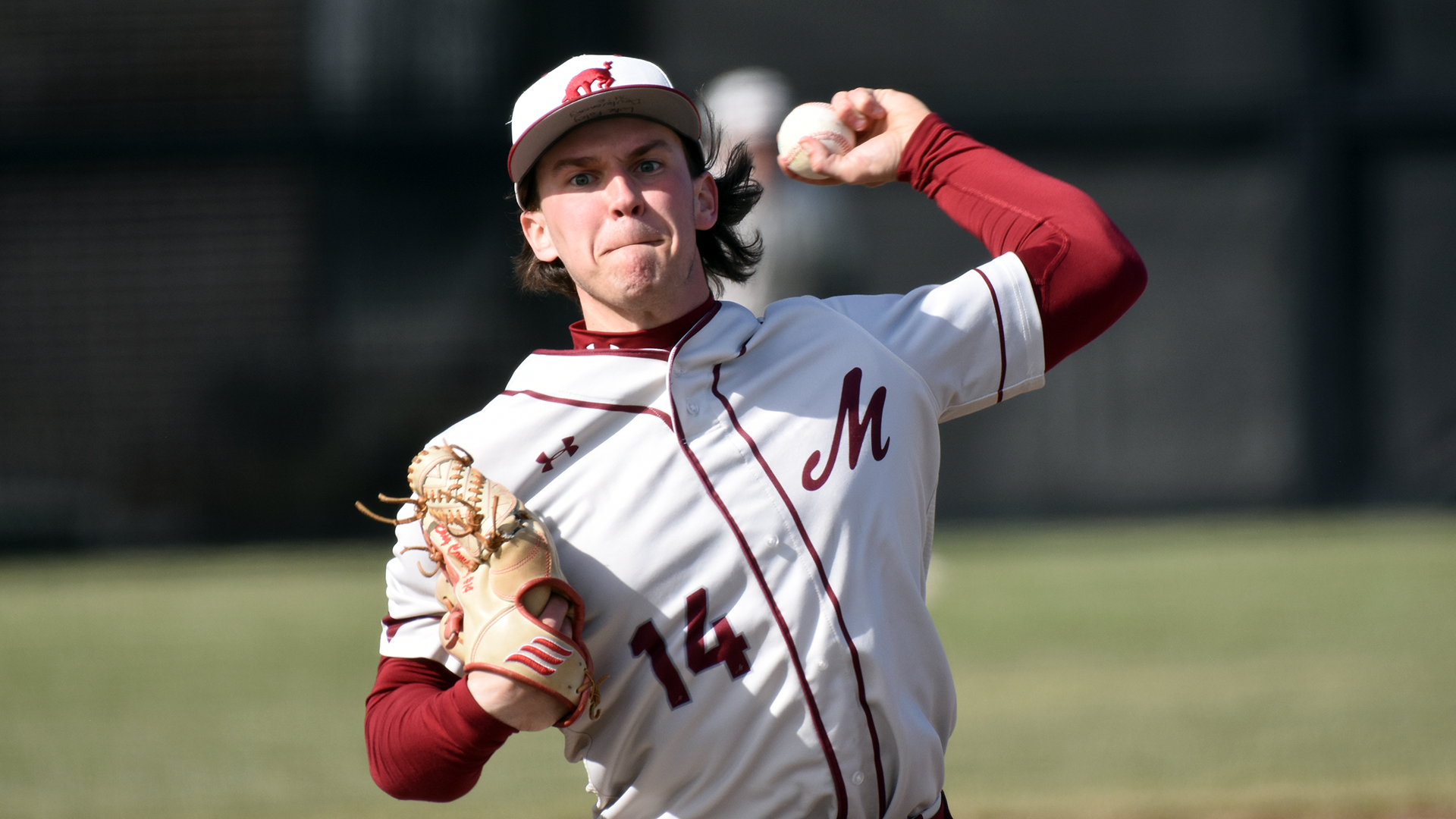 a left-handed pitcher in a white uniform delivers a pitch while facing the camera