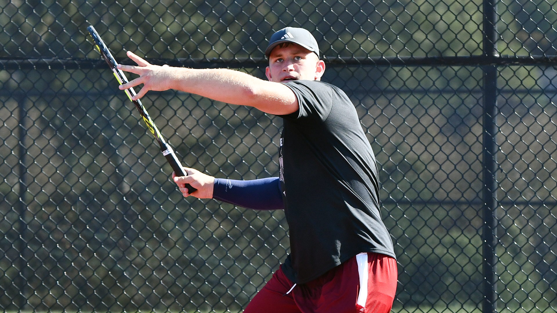a tennis player in a black shirt and red shorts getting ready to return a shot