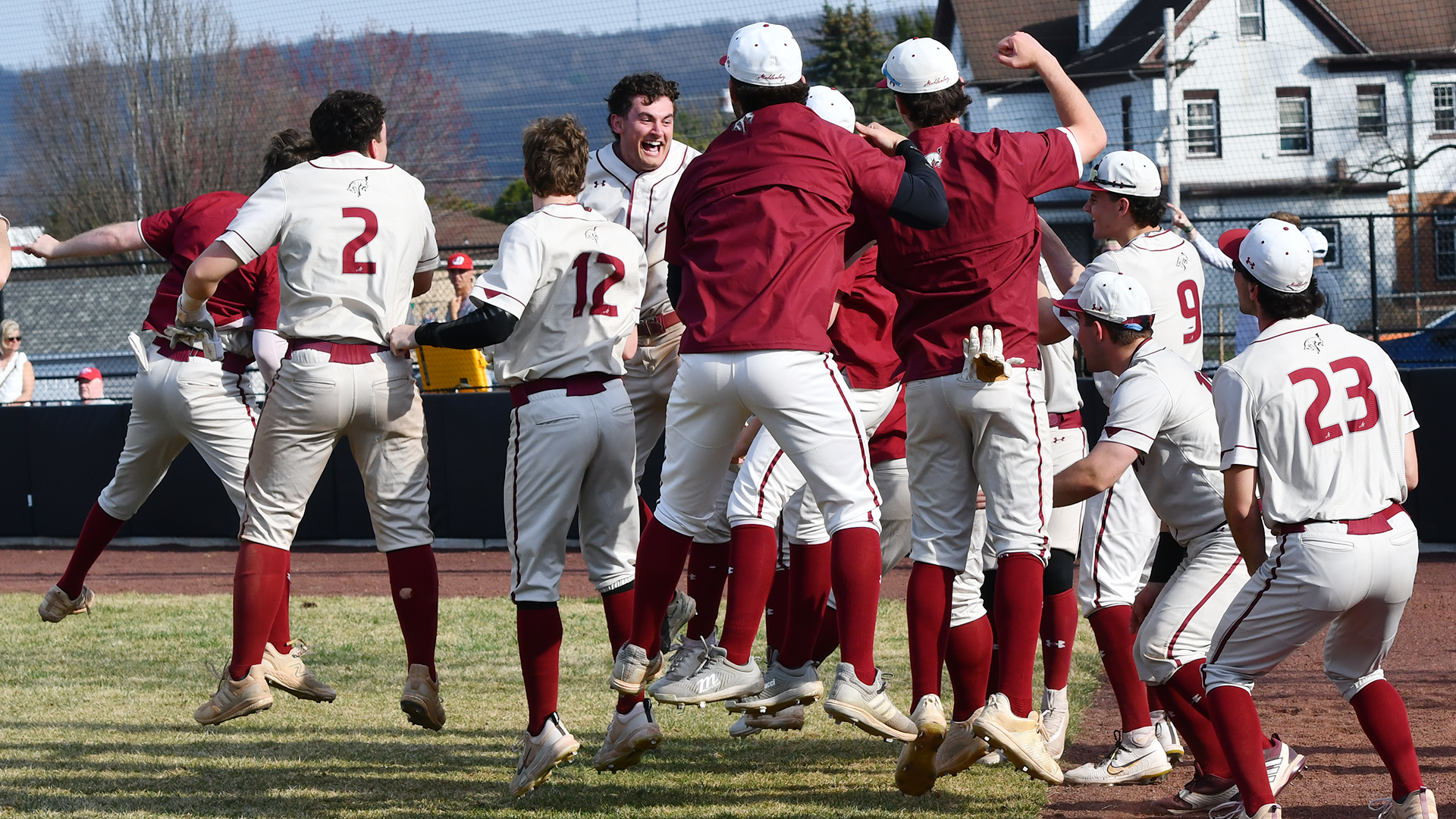 baseball players in white uniforms and red jackets celebrating a home run
