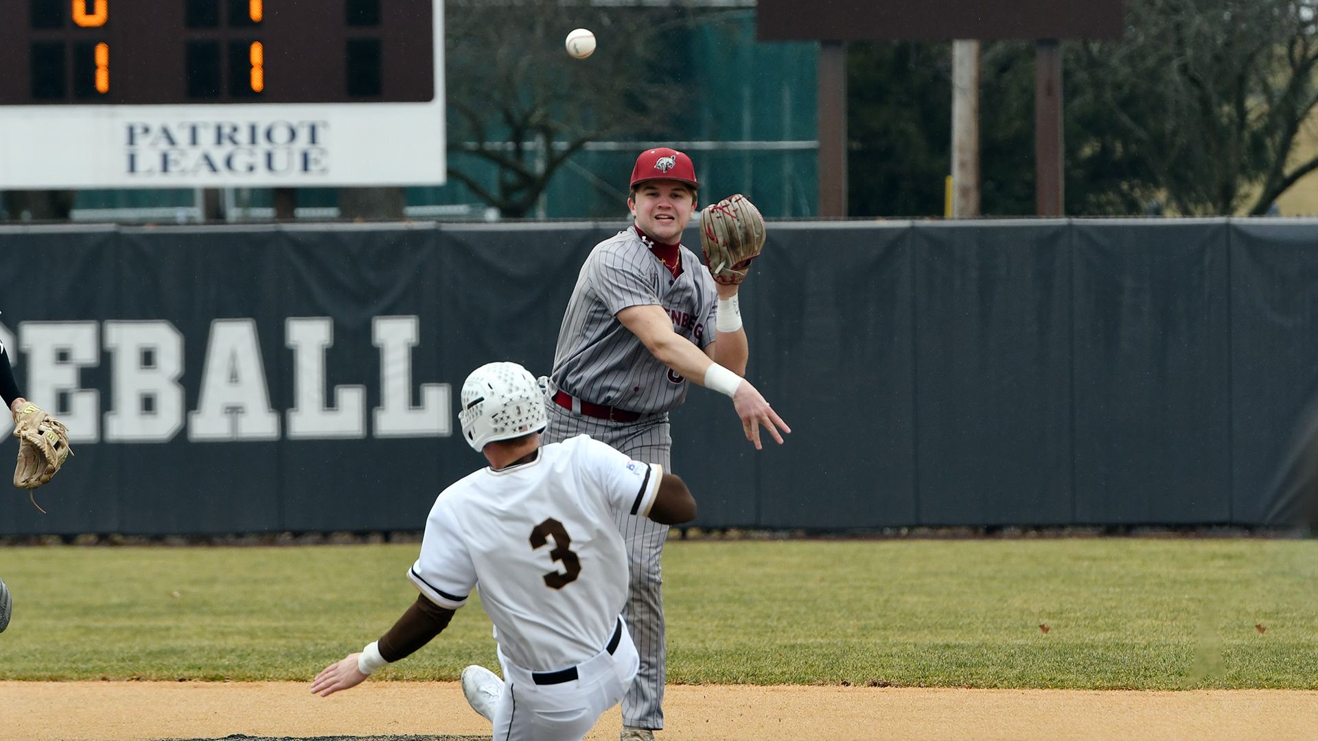 a baseball player in a grey pinstriped uniform and red hat throws the ball to first as a player with a white uniform and white helmet slides into second base