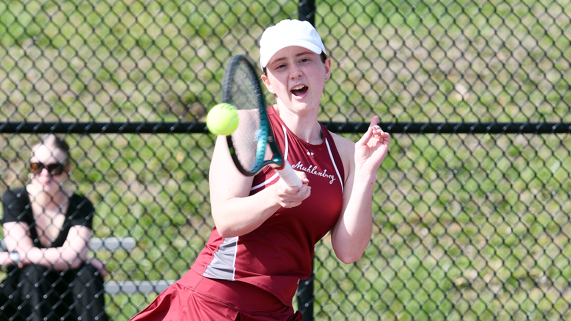 a tennis player in a red uniform and white visor hits a forehand