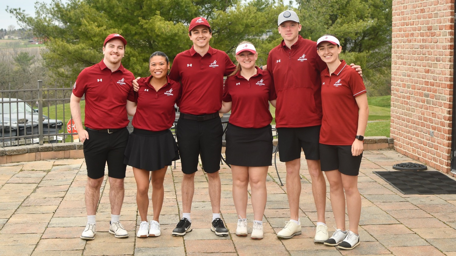 Six golfers in red polos stand and pose for a photo outside