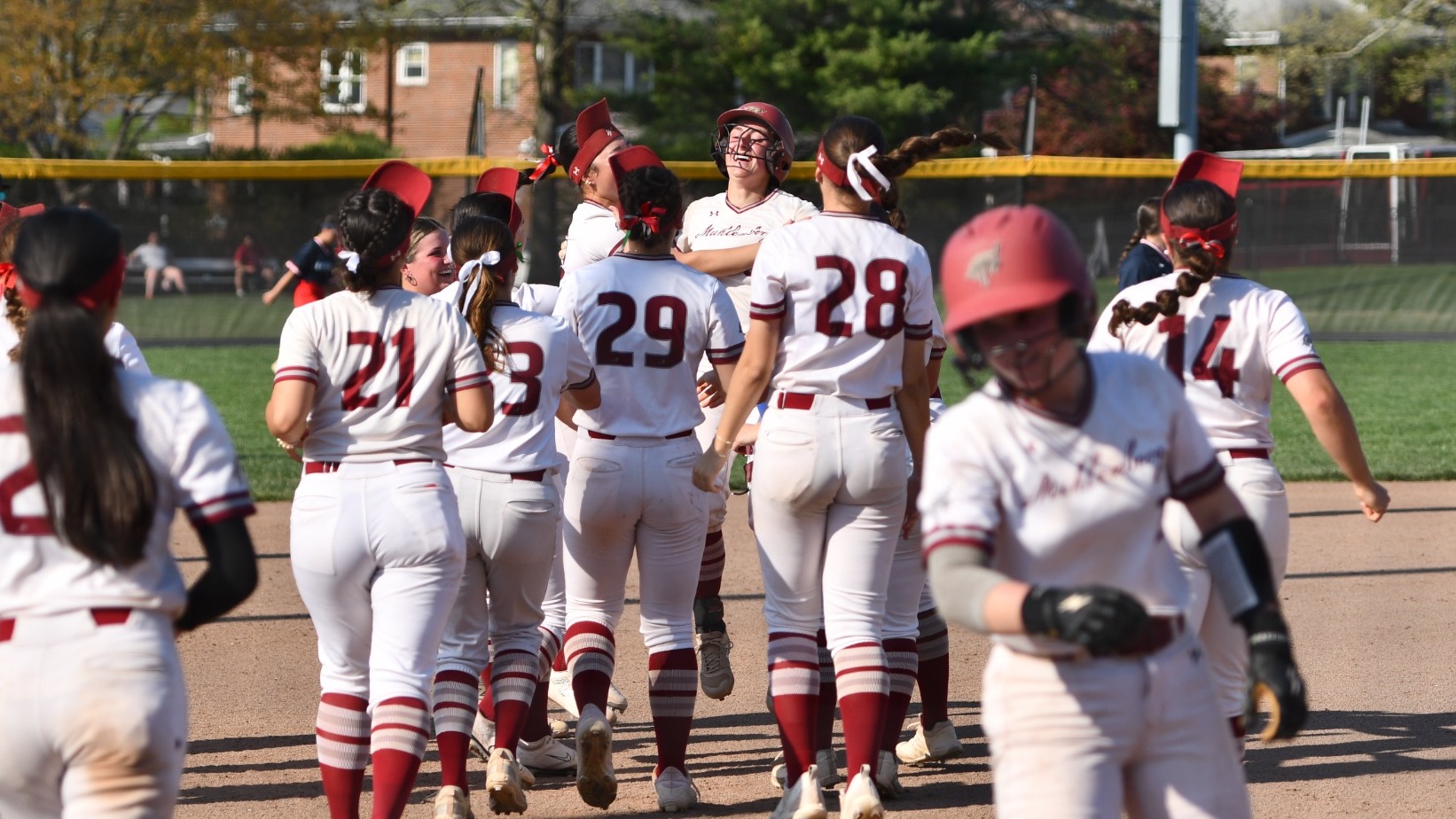 Muhlenberg softball players run together on the field to celebrate, gathering around Scooter Hulsen after her walk-off double.