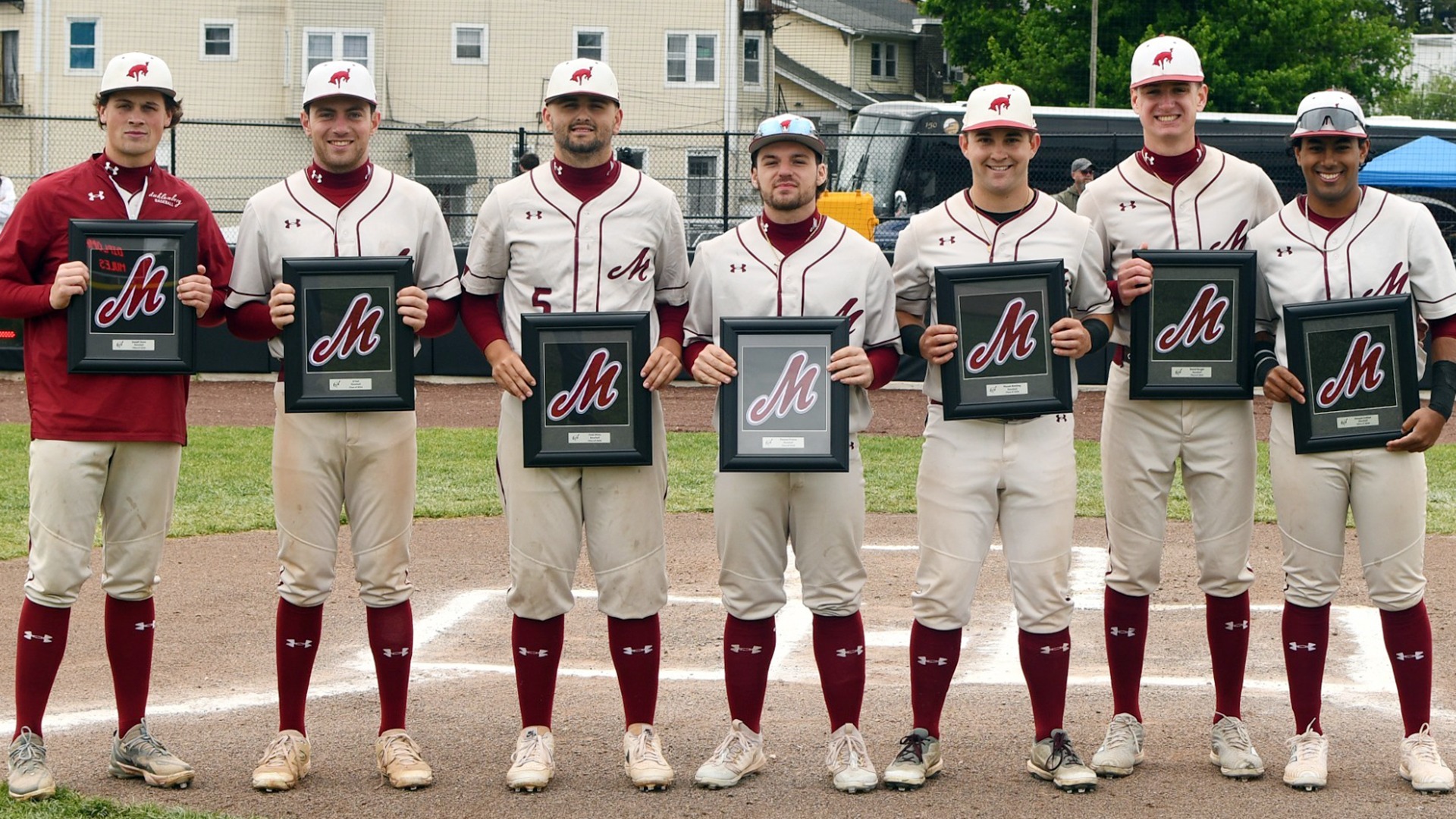 Seven baseball players, six in white and one in red, standing and posing for a photo while holding plaques