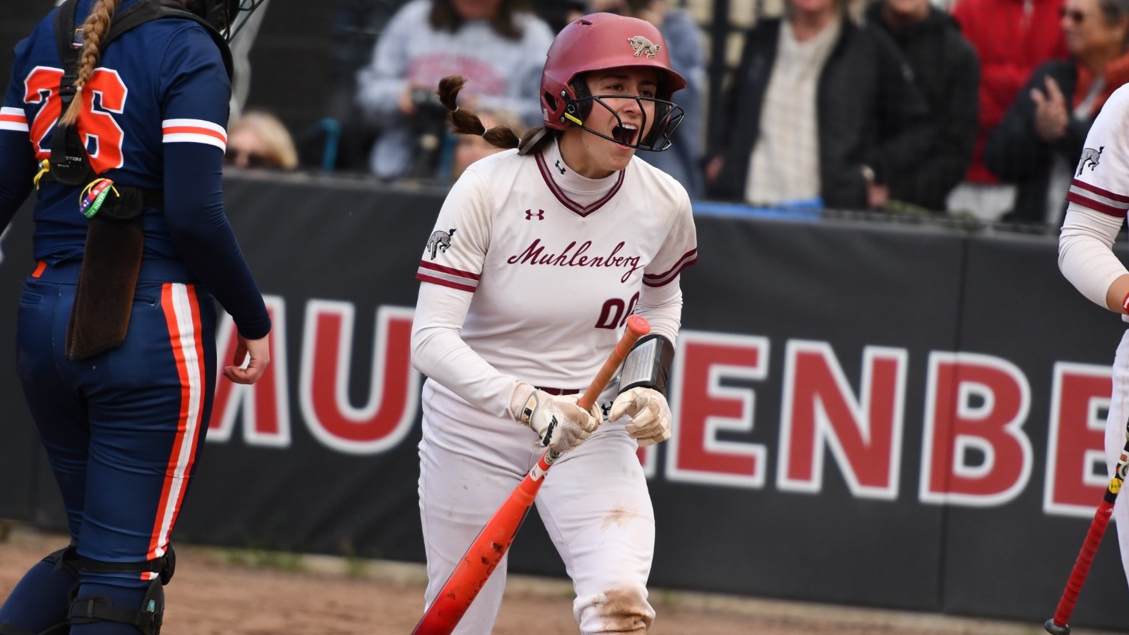 A softball player wearing white screams in celebration while holding a bat