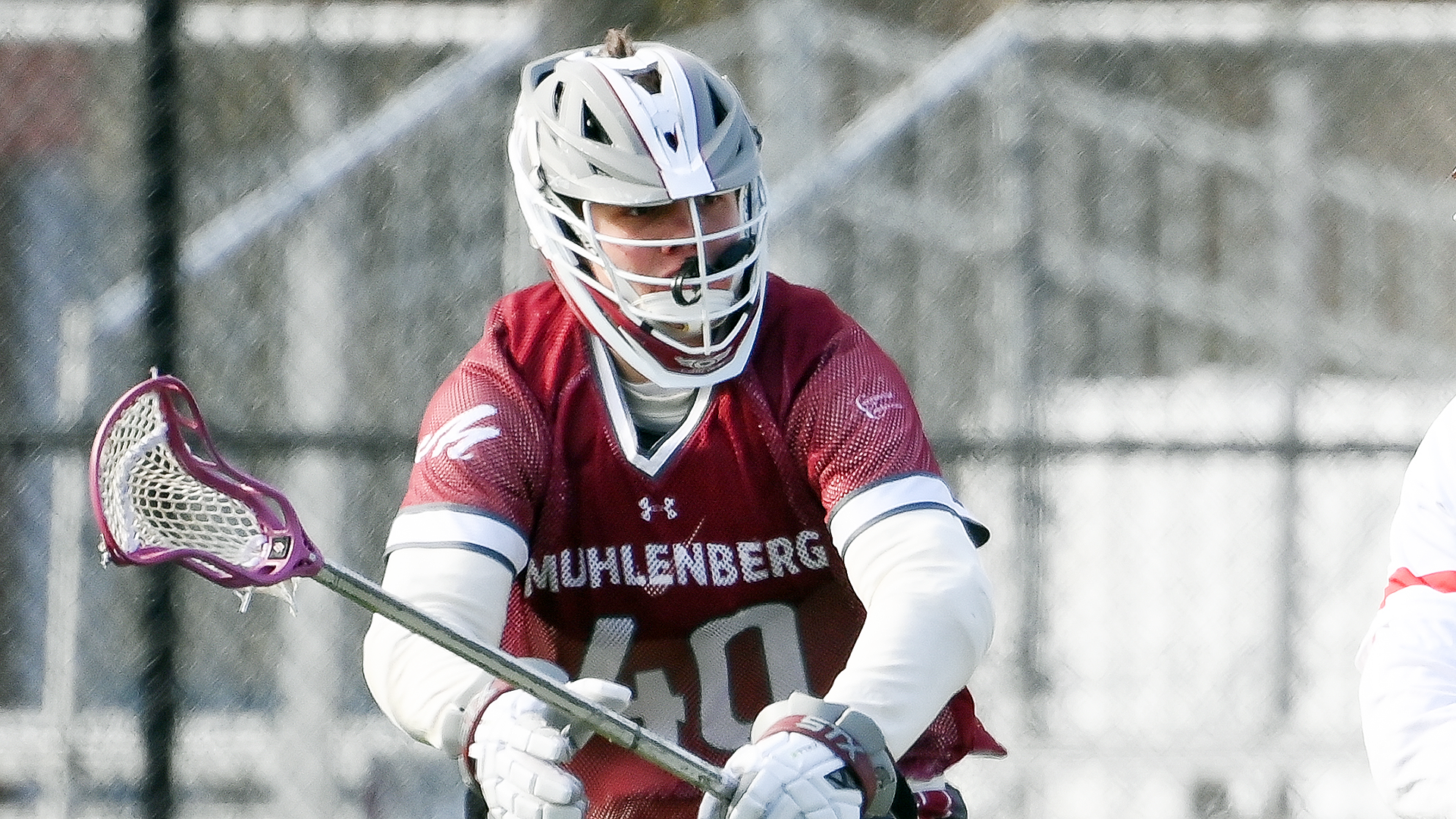 a lacrosse player in a red jersey wearing number 40 in a defensive stance