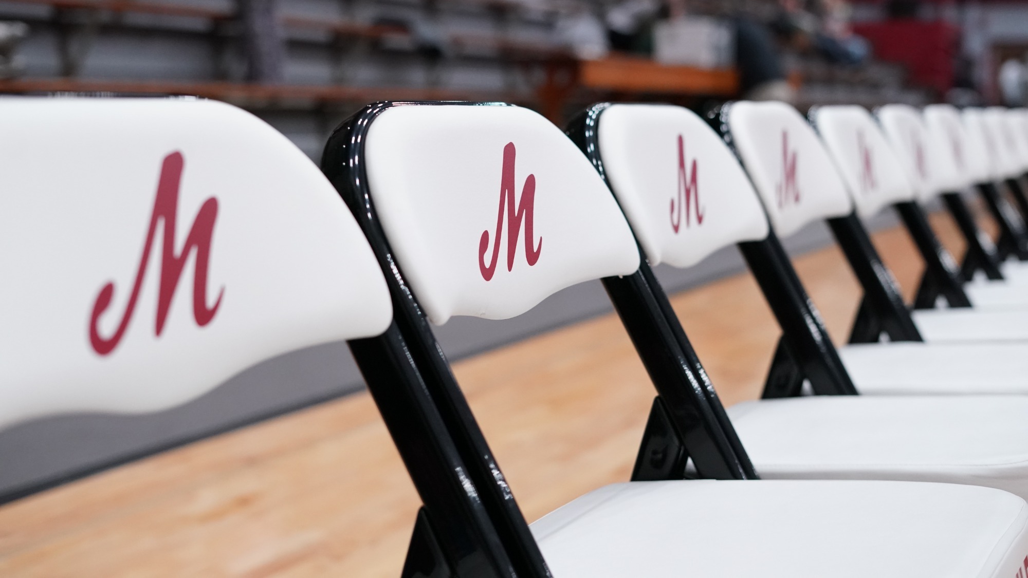A row of white basketball chairs with the Muhlenberg logo 