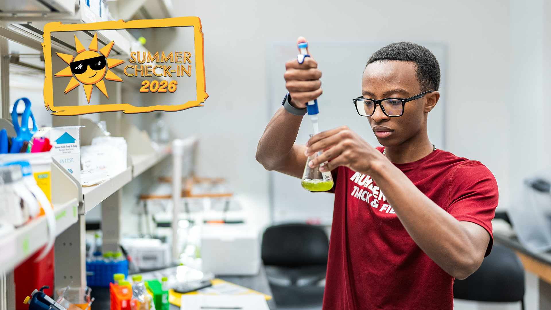 a student in a lab wearing a red t-shirt plunging yellow-green liquid into a beaker