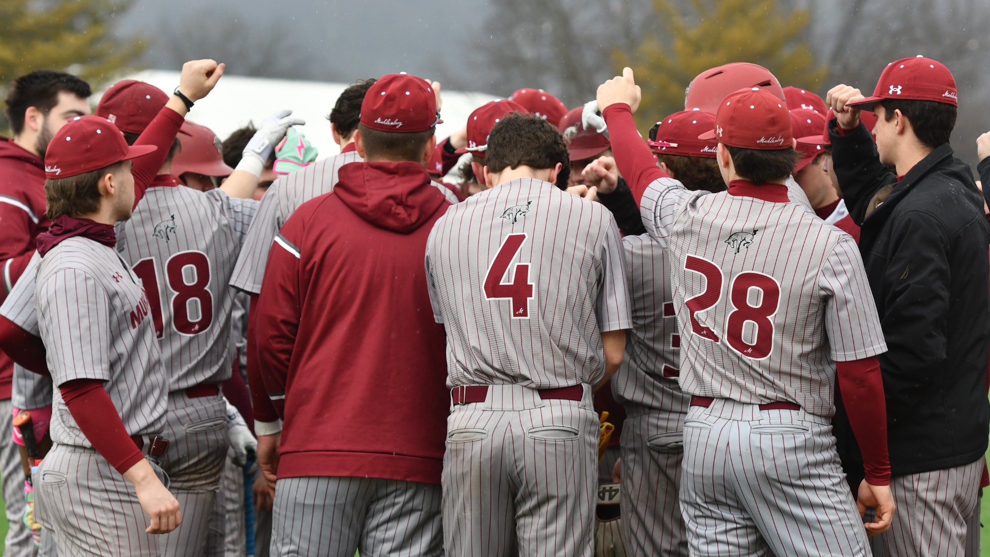 A baseball team dressed in grey and red huddles up