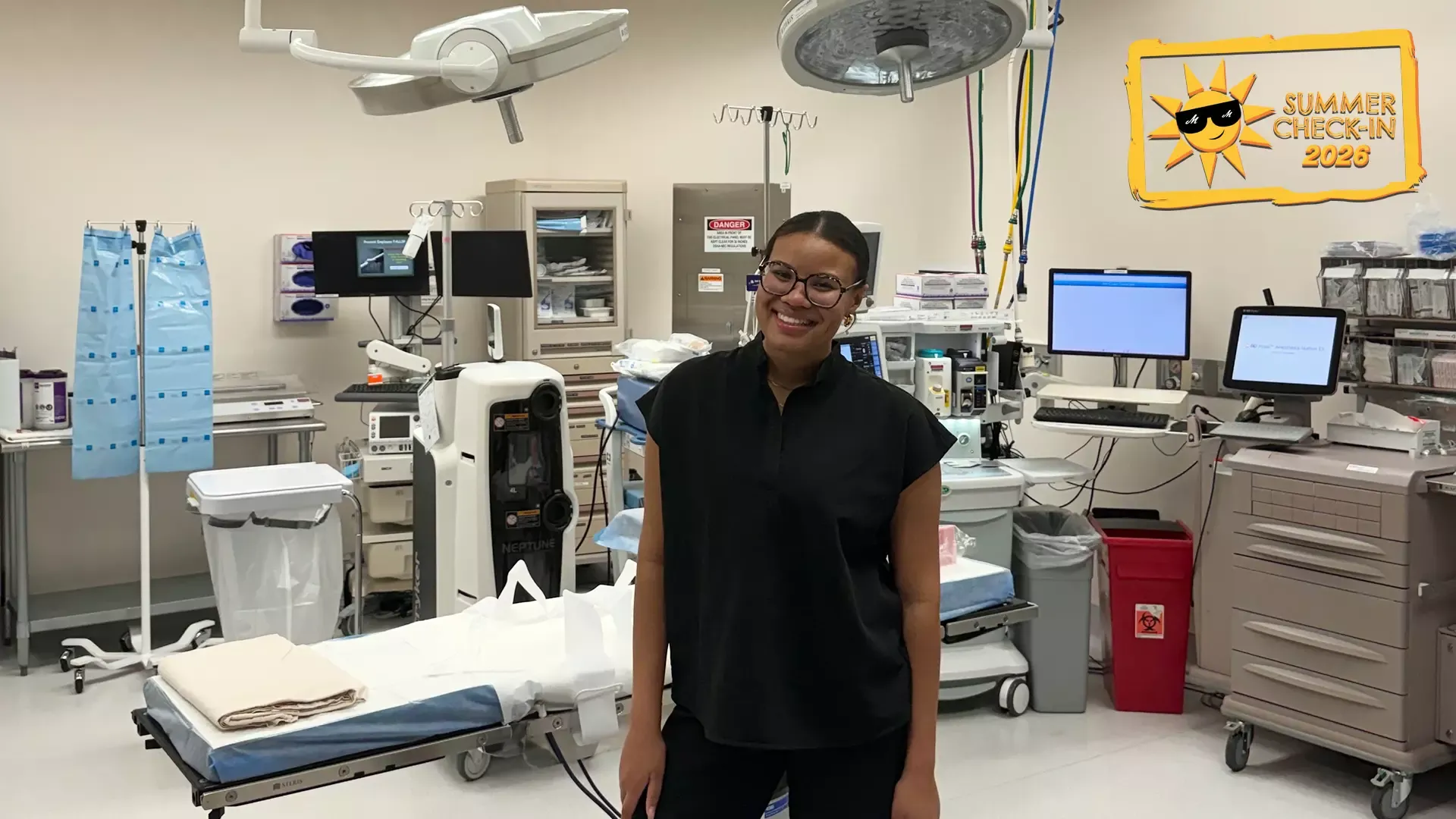 a young woman in a black outfit standing in a hospital room full of medical equipment