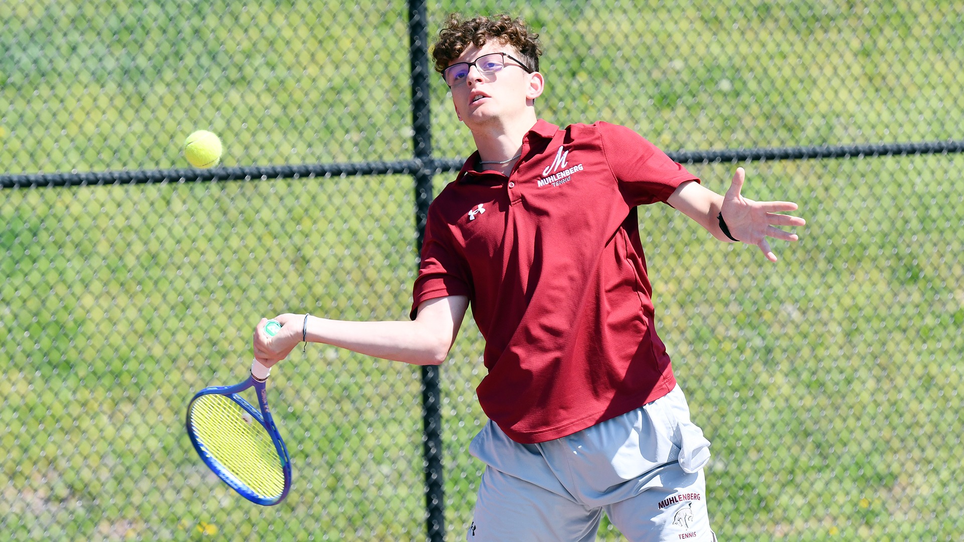 a tennis player in a red shirt hitting a forehand