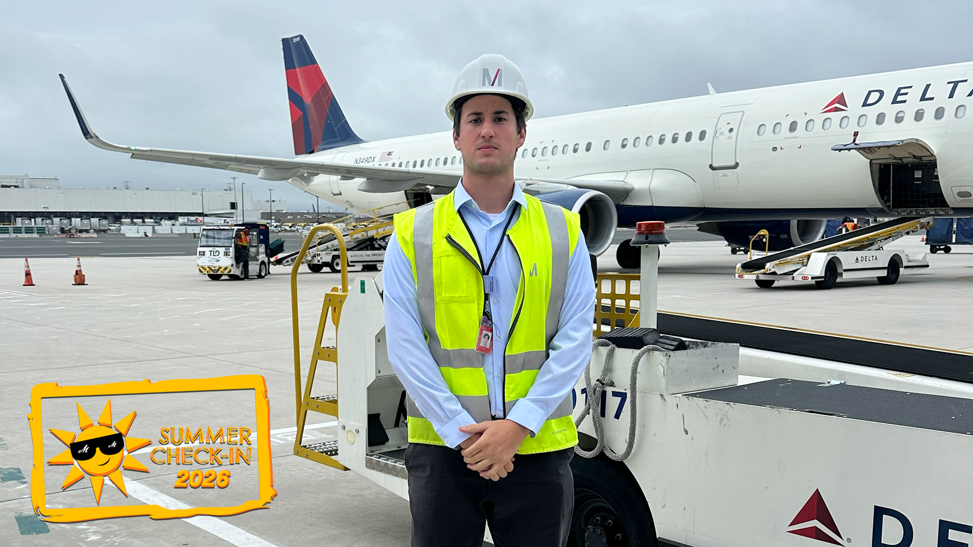 a young man in a white hardhat and yellow protective vest standing outdoors in front of an airplane