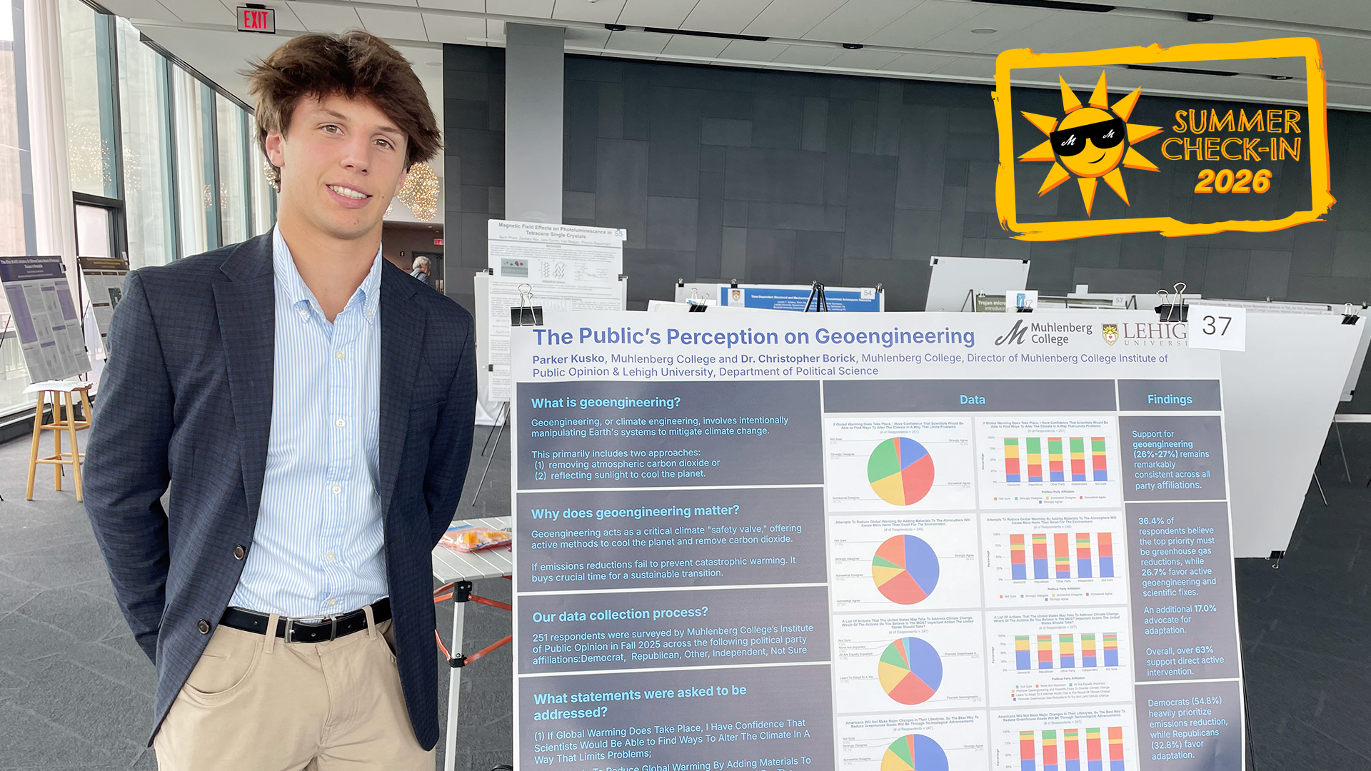 a young man in a blue blazer posing in front of an informational poster titled 