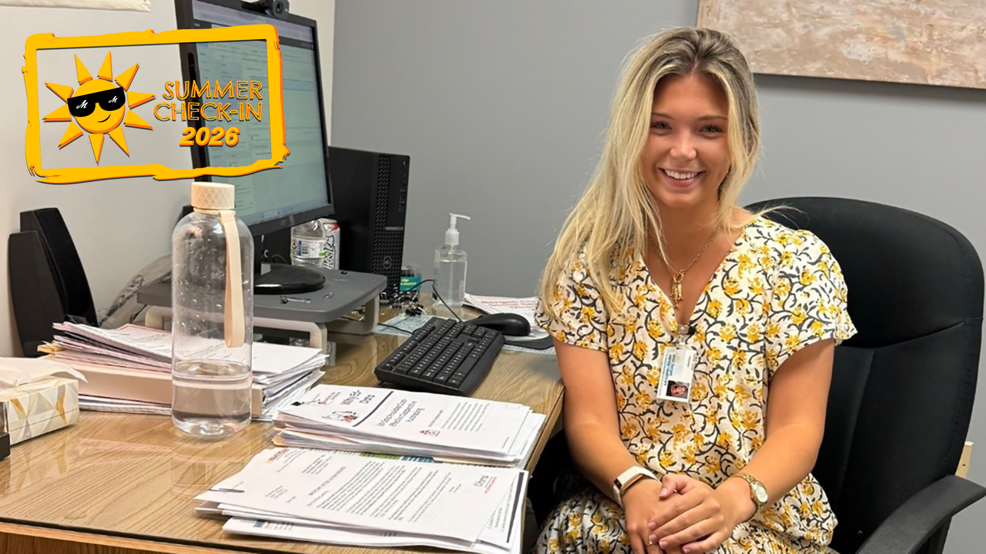 a young woman in a white dress with black and yellow decorations sitting at an office desk
