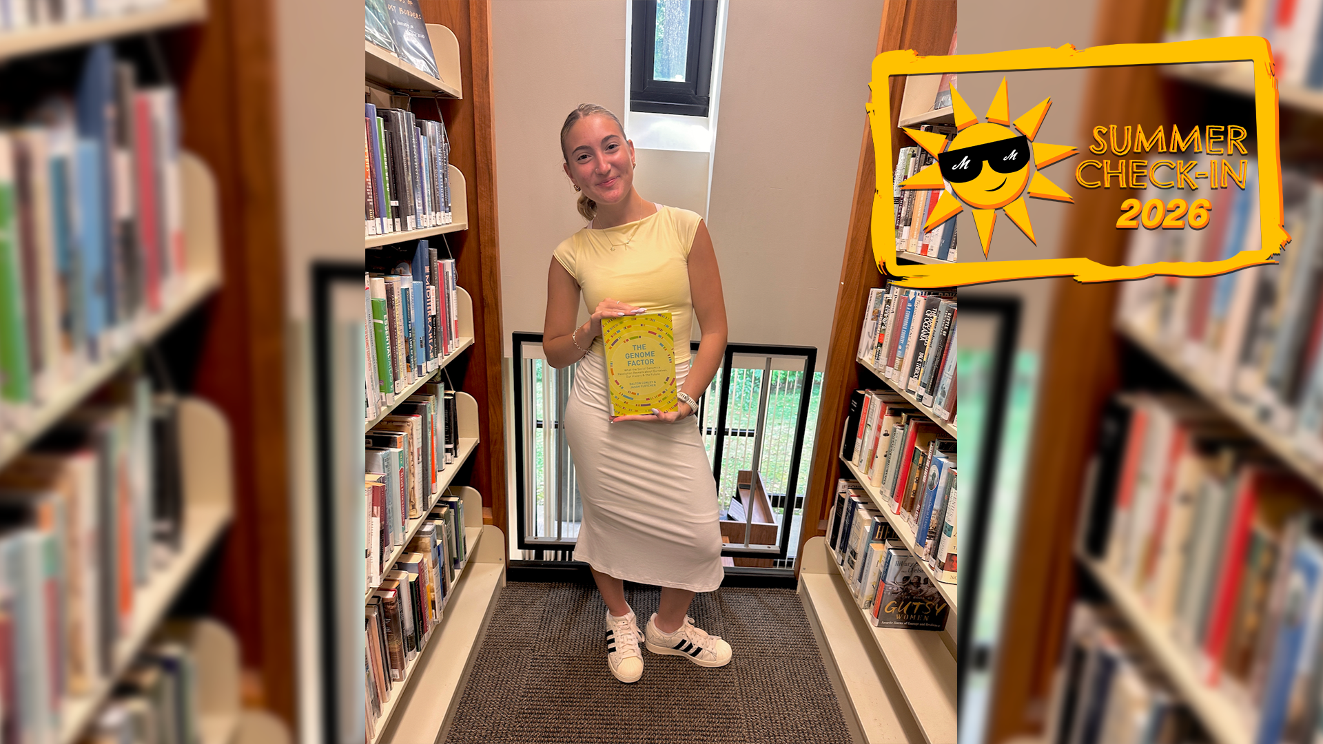 a young woman in a yellow top and white dress standing in between aisles of library books and holding a book title The Genome Factor