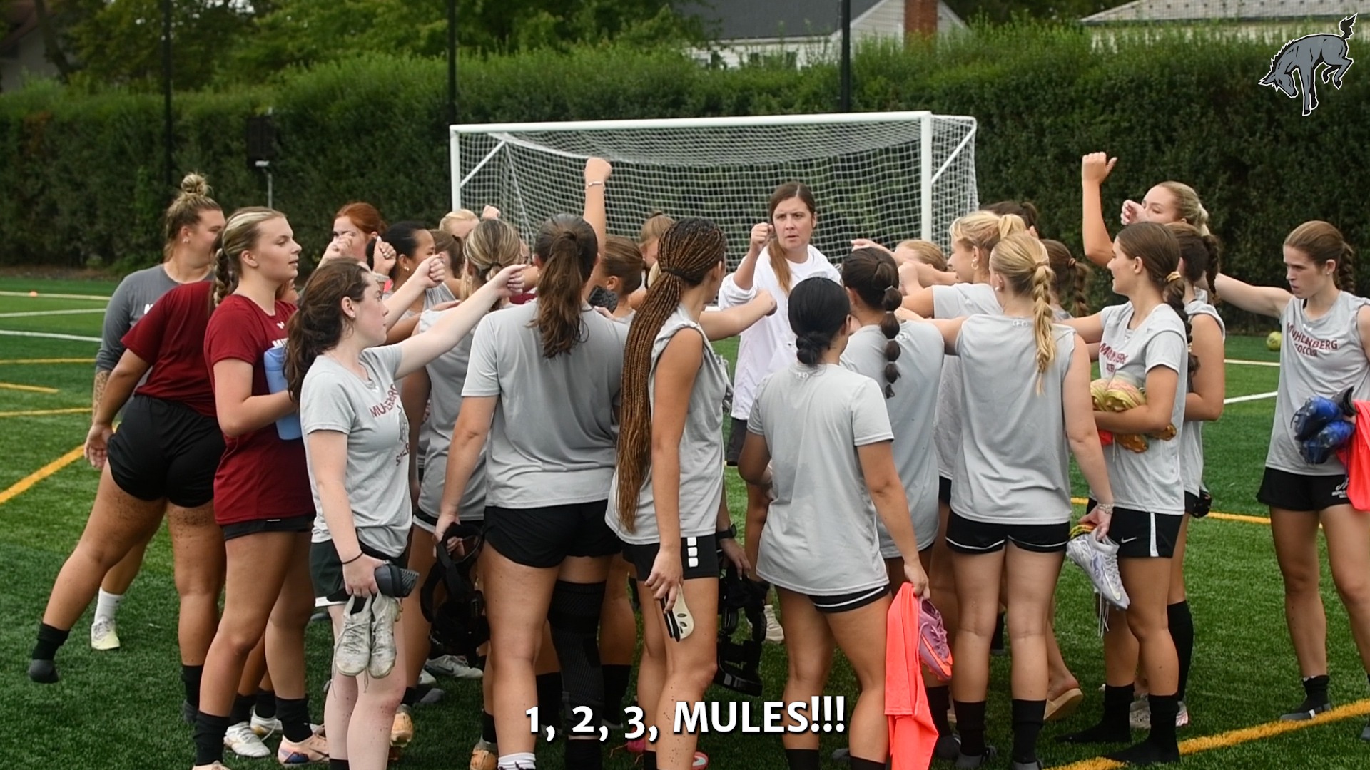 women's soccer players in grey t-shirts and black shorts standing in a circle
