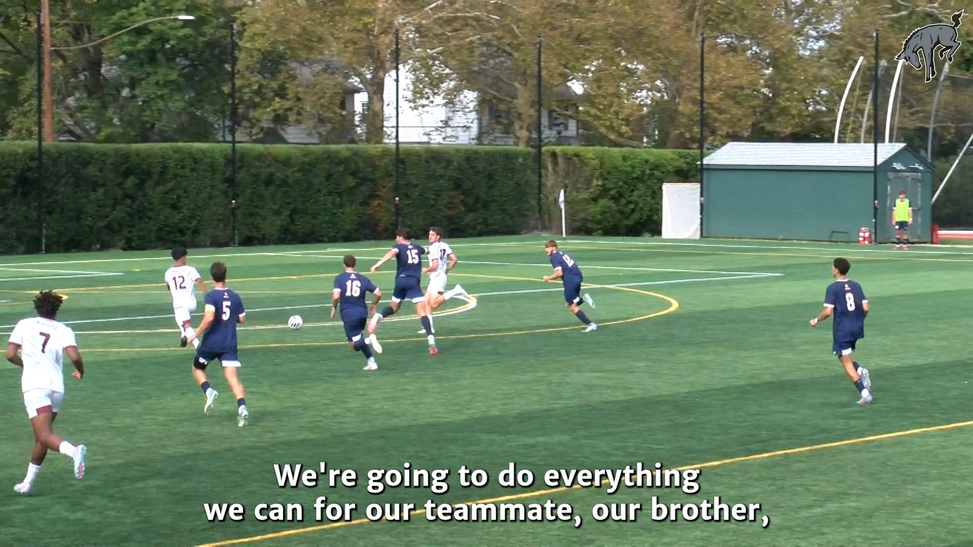 soccer action on a green turf field with players in blue and white uniforms