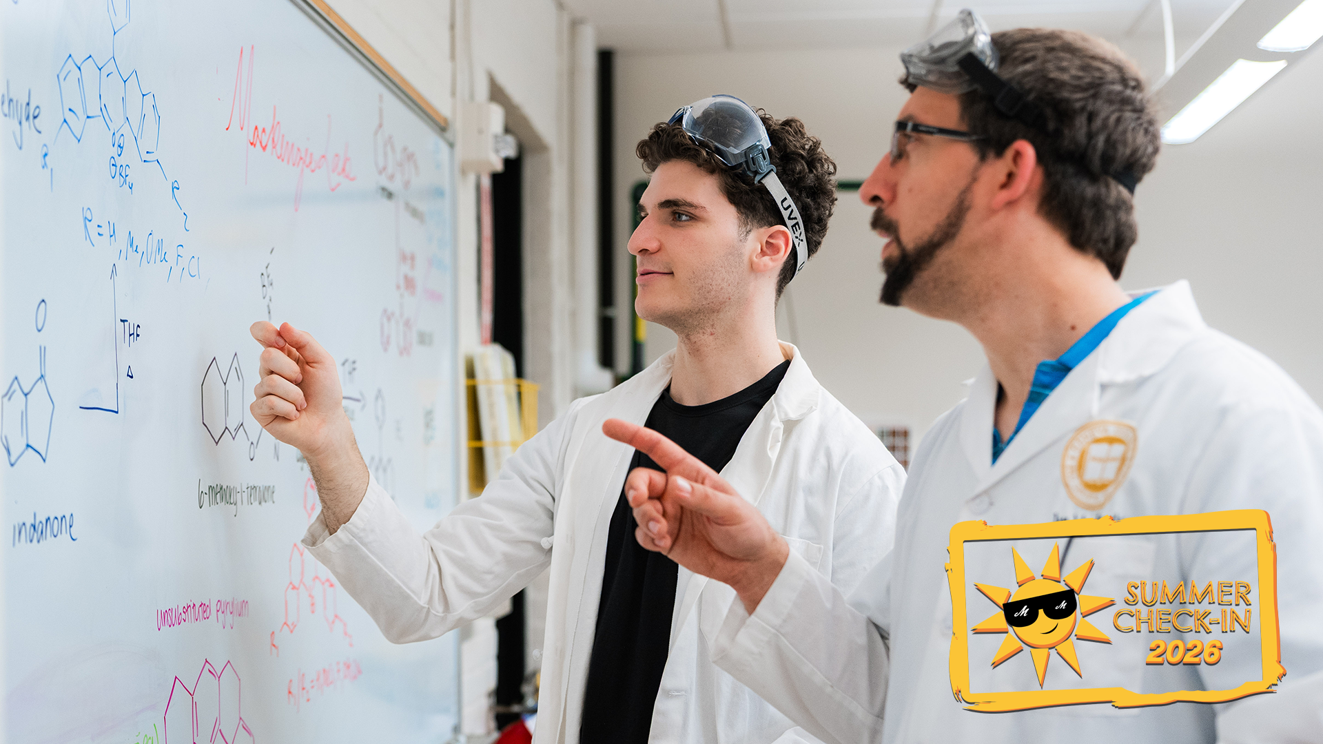 two men in white lab coats and goggles on their heads looking at chemical diagrams on a whiteboard